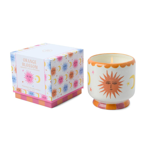Candle with sun design and matching box on a white background