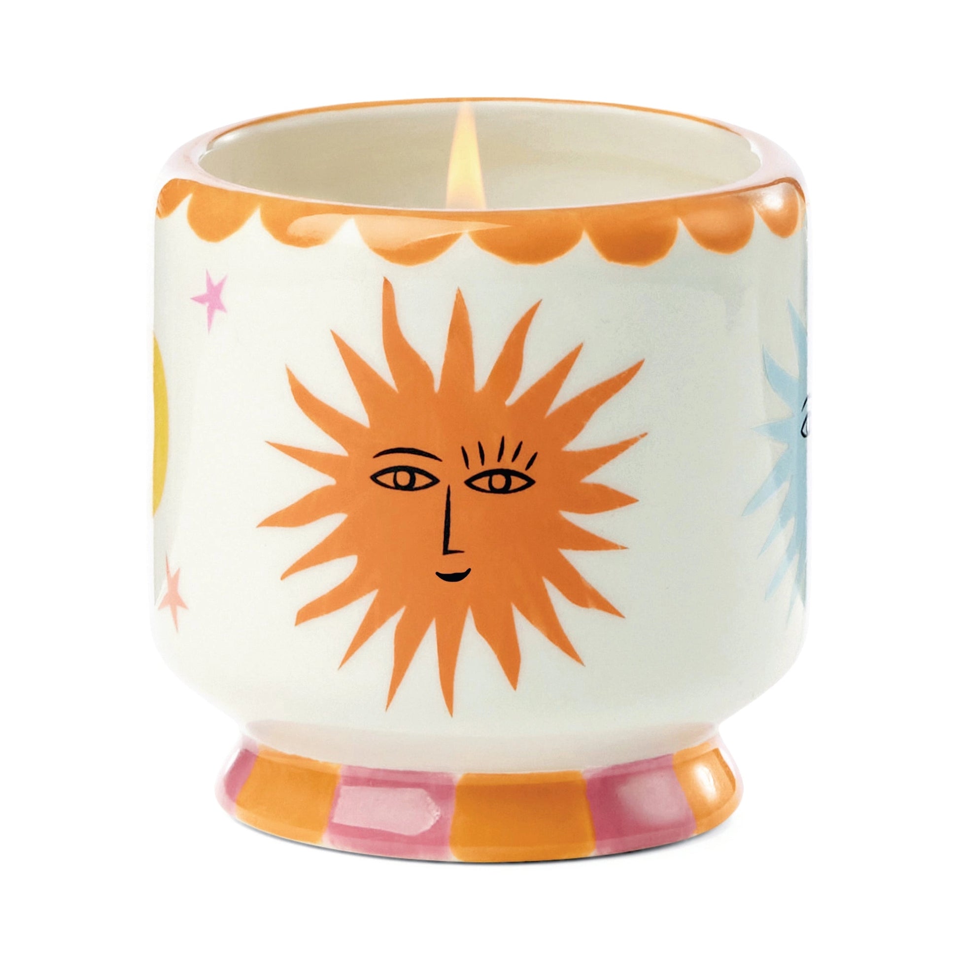 A ceramic candle holder with a white body, featuring a large orange sun face design on the front, a pink crescent moon on the side, and a pink and orange patterned base.
