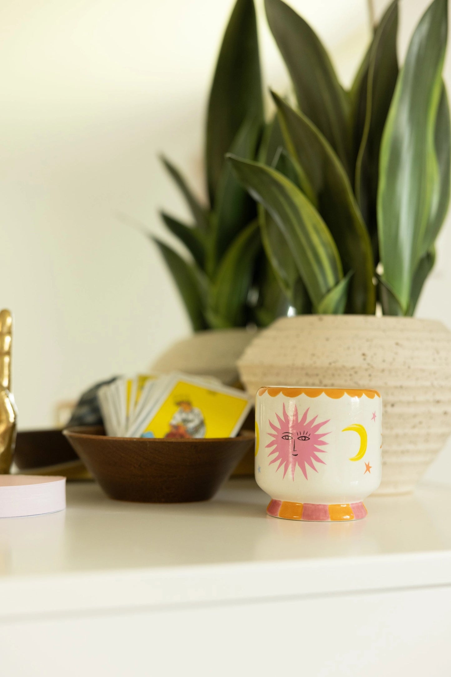 Decorative candle with sun design on a surface with a plant in the background
