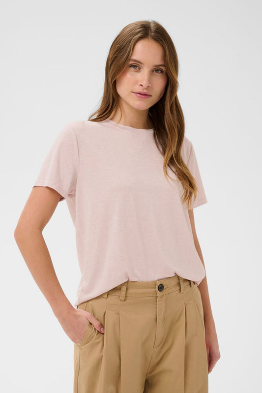 Woman wearing a light pink t-shirt and beige pants on a white background