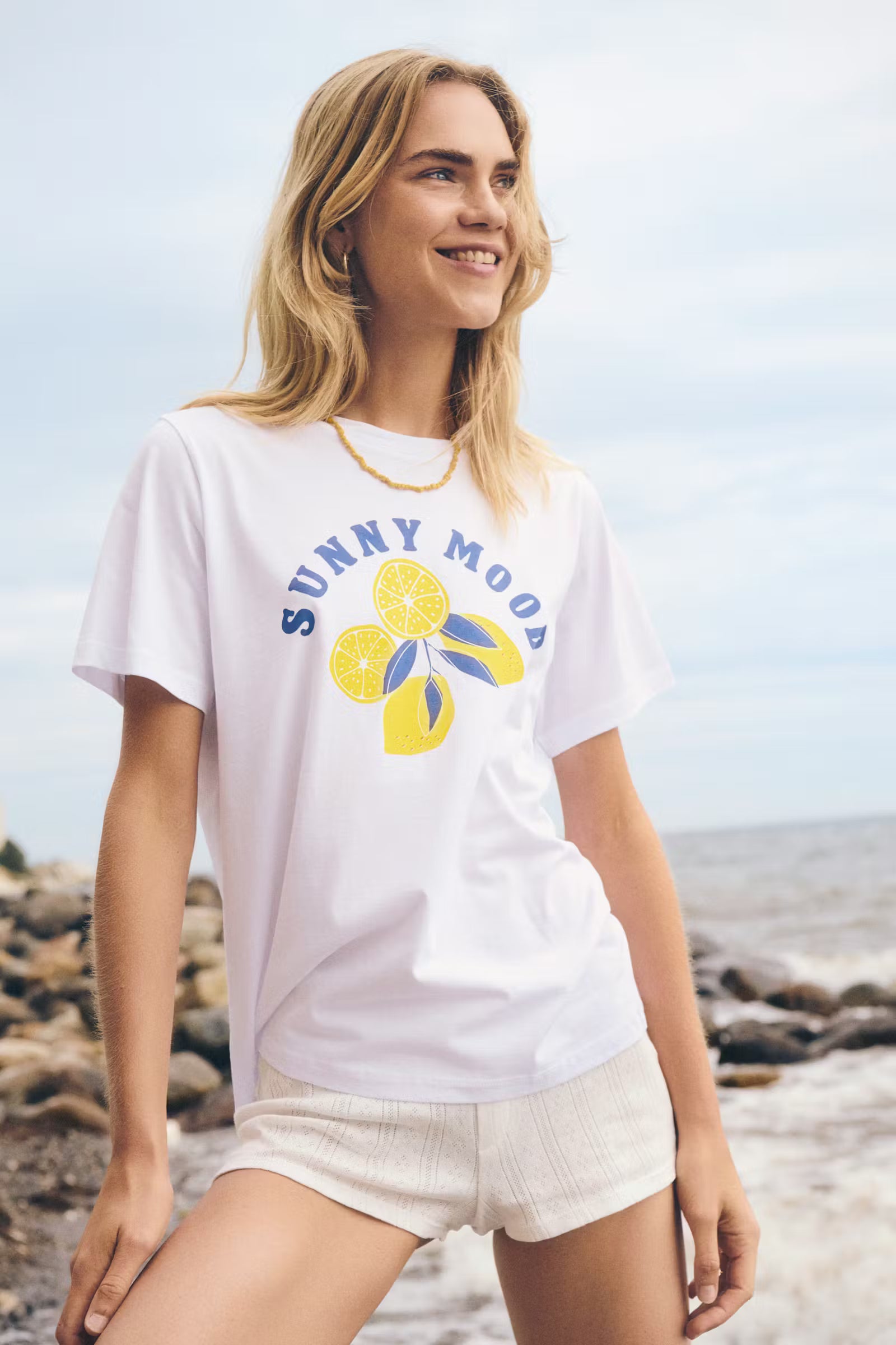 Woman wearing a white t-shirt with a lemon design on a beach