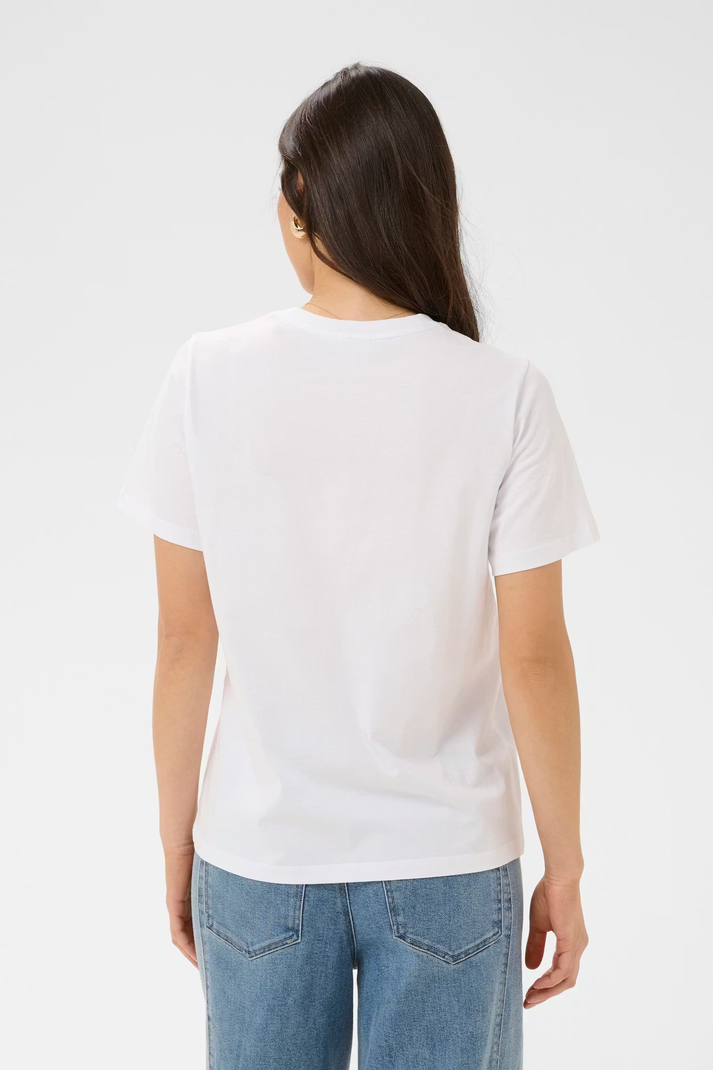 Person wearing a plain white t-shirt and blue jeans on a light gray background