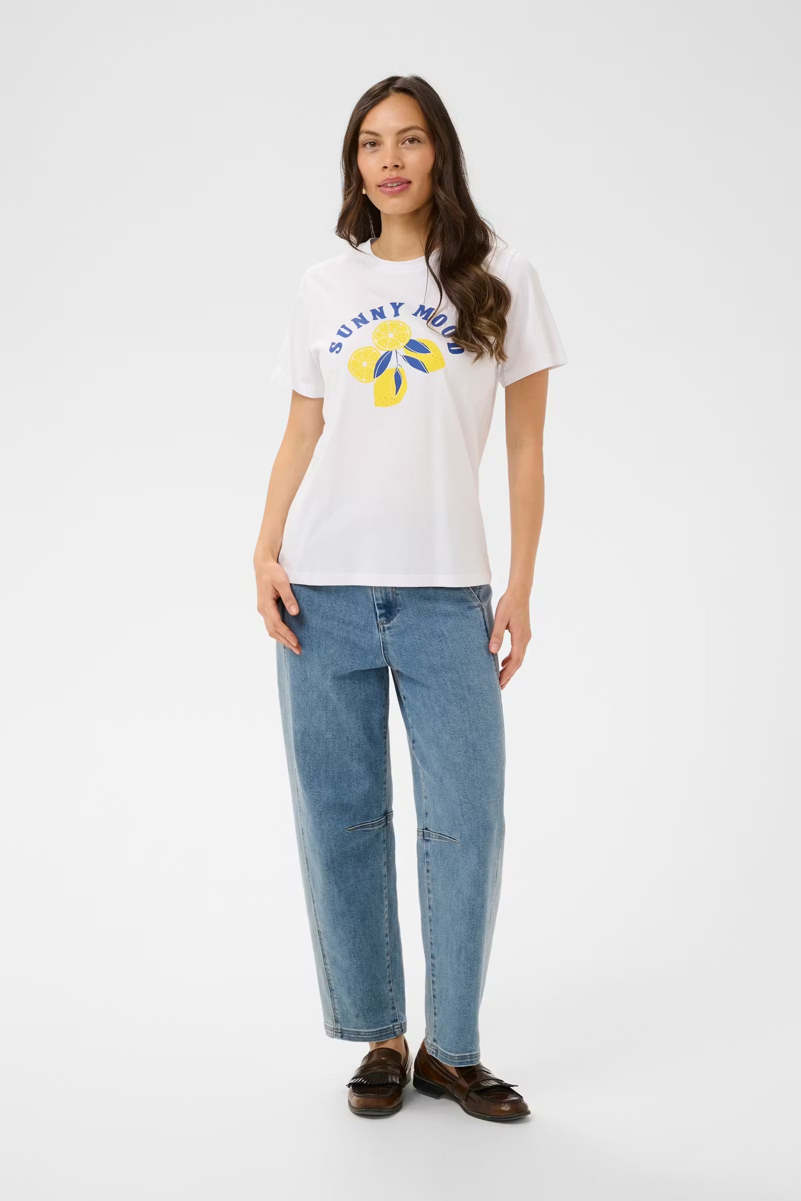 Woman wearing a white t-shirt with a colorful graphic and blue jeans on a white background