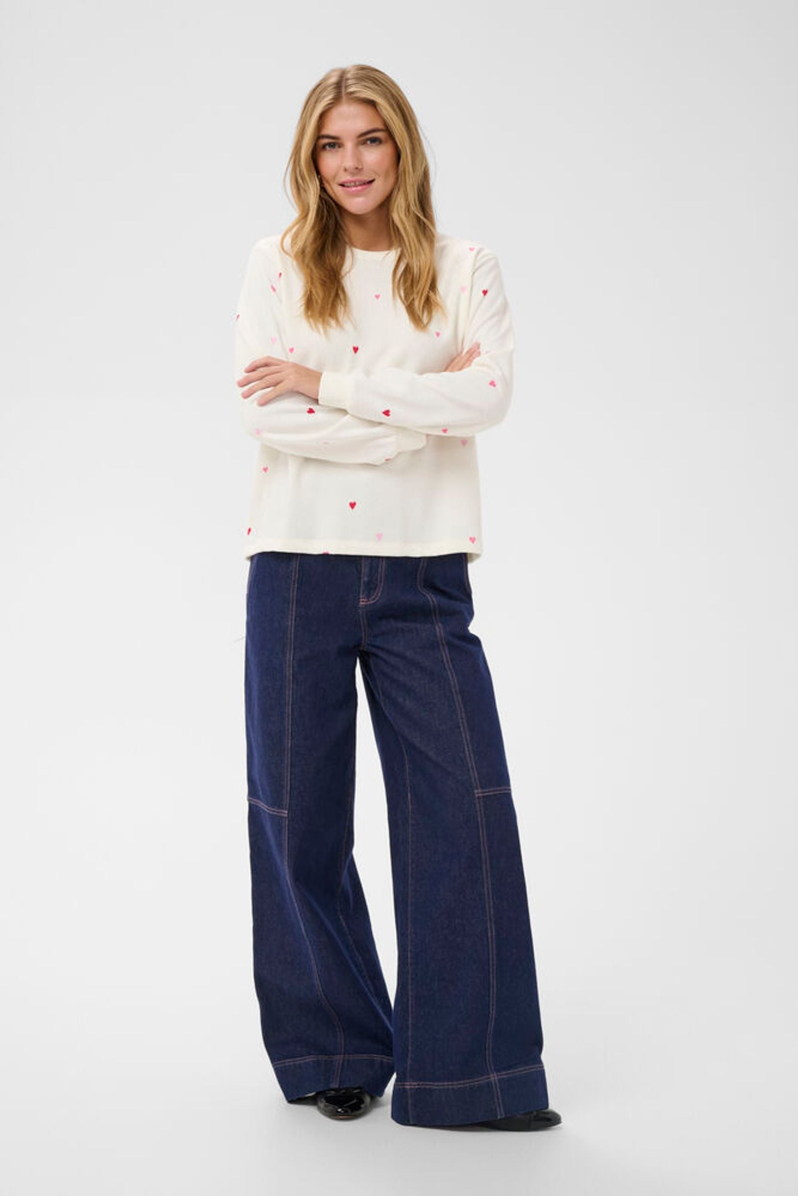 Woman wearing a white sweater and blue plaid pants on a white background