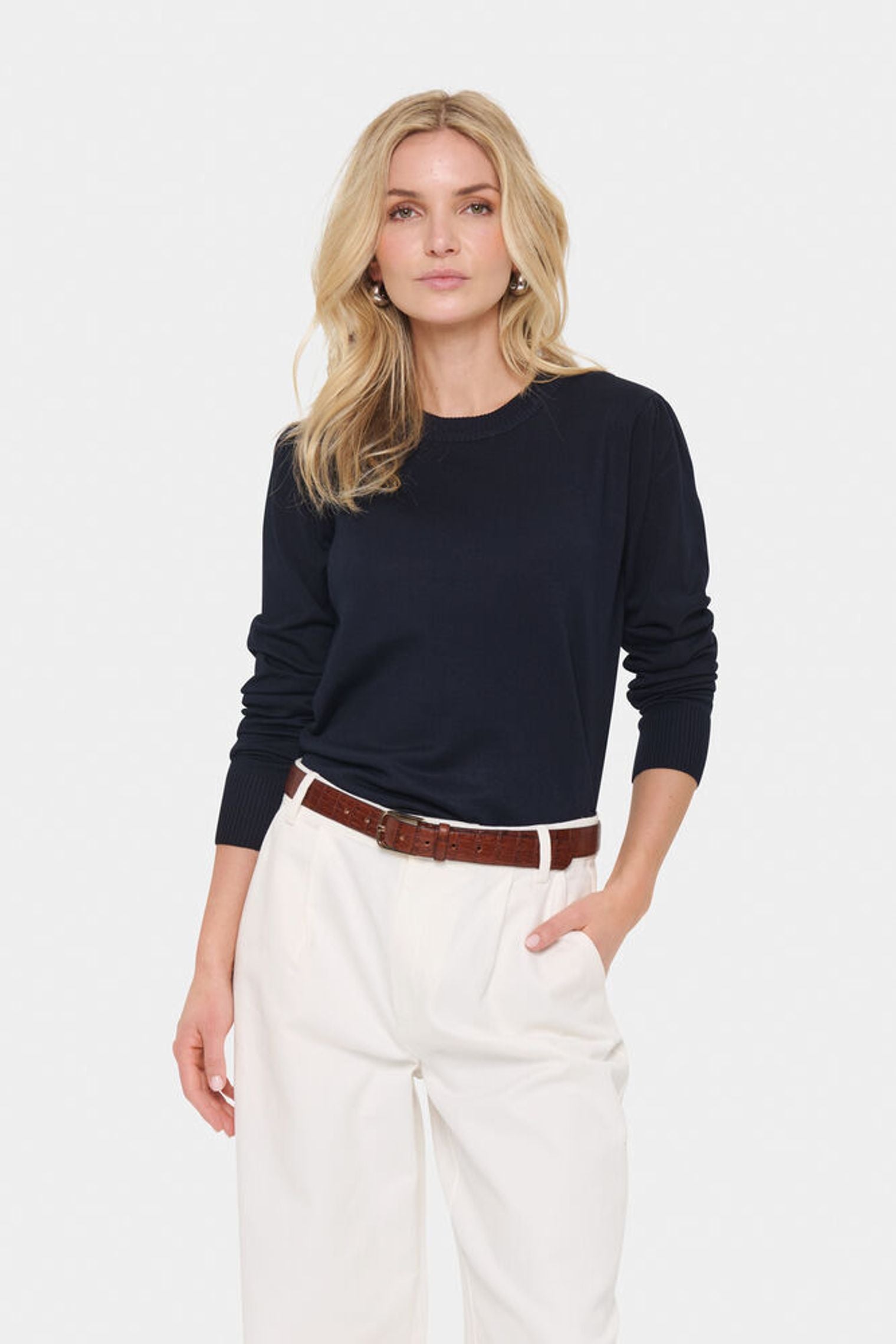 Model in cream trousers and navy blue jumper