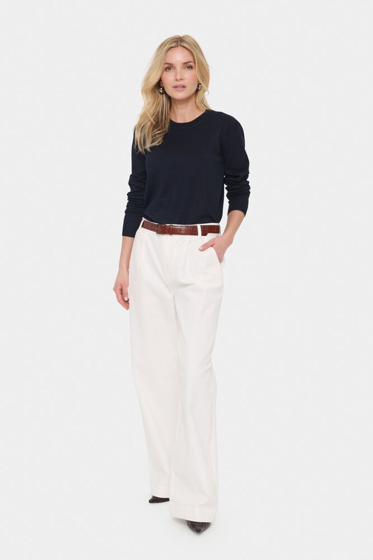 Model in cream trousers and navy blue jumper