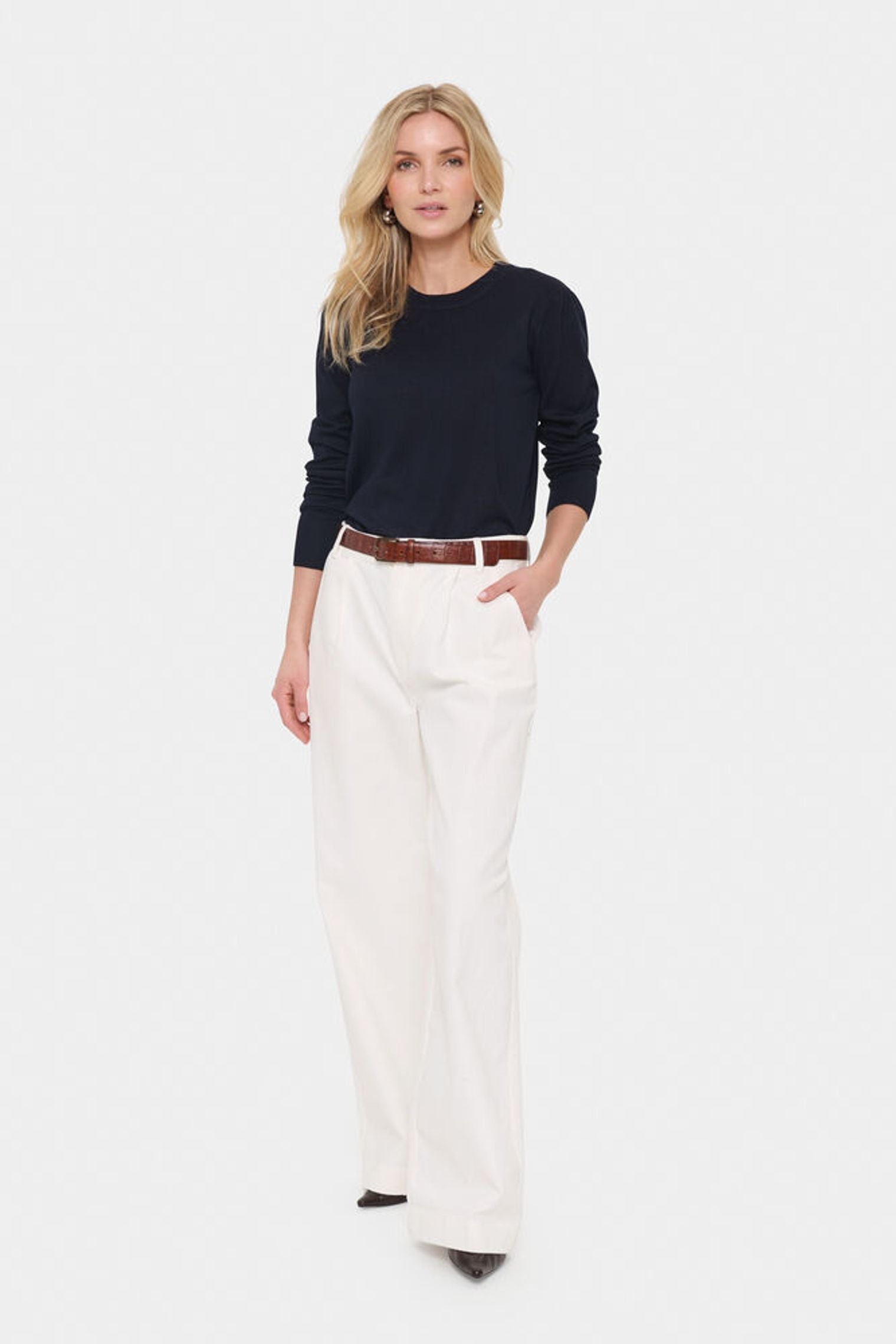 Model in cream trousers and navy blue jumper