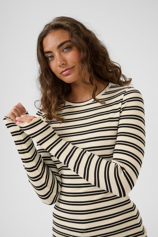 Woman wearing a black and white striped long-sleeve top against a plain background