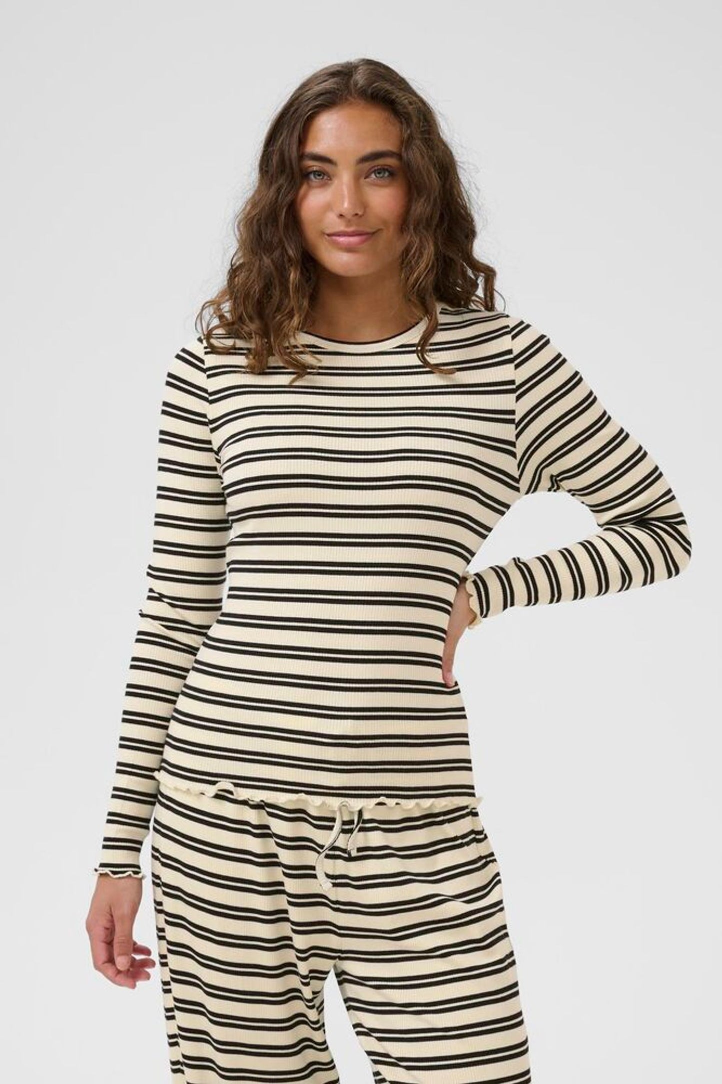 Woman wearing a striped long-sleeve top and pants on a white background