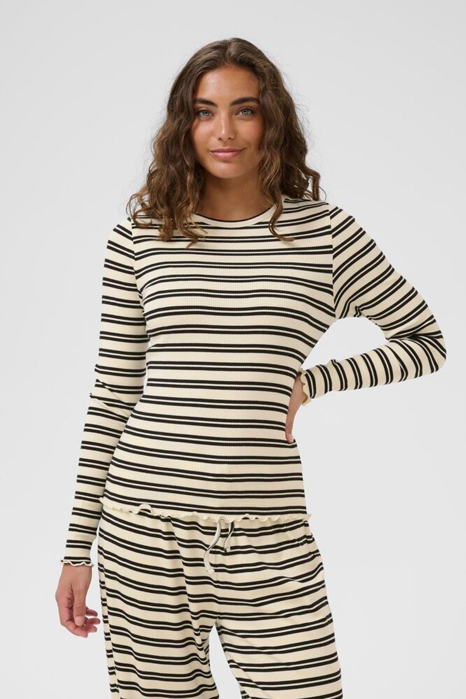 Woman wearing a striped long-sleeve top and pants on a white background