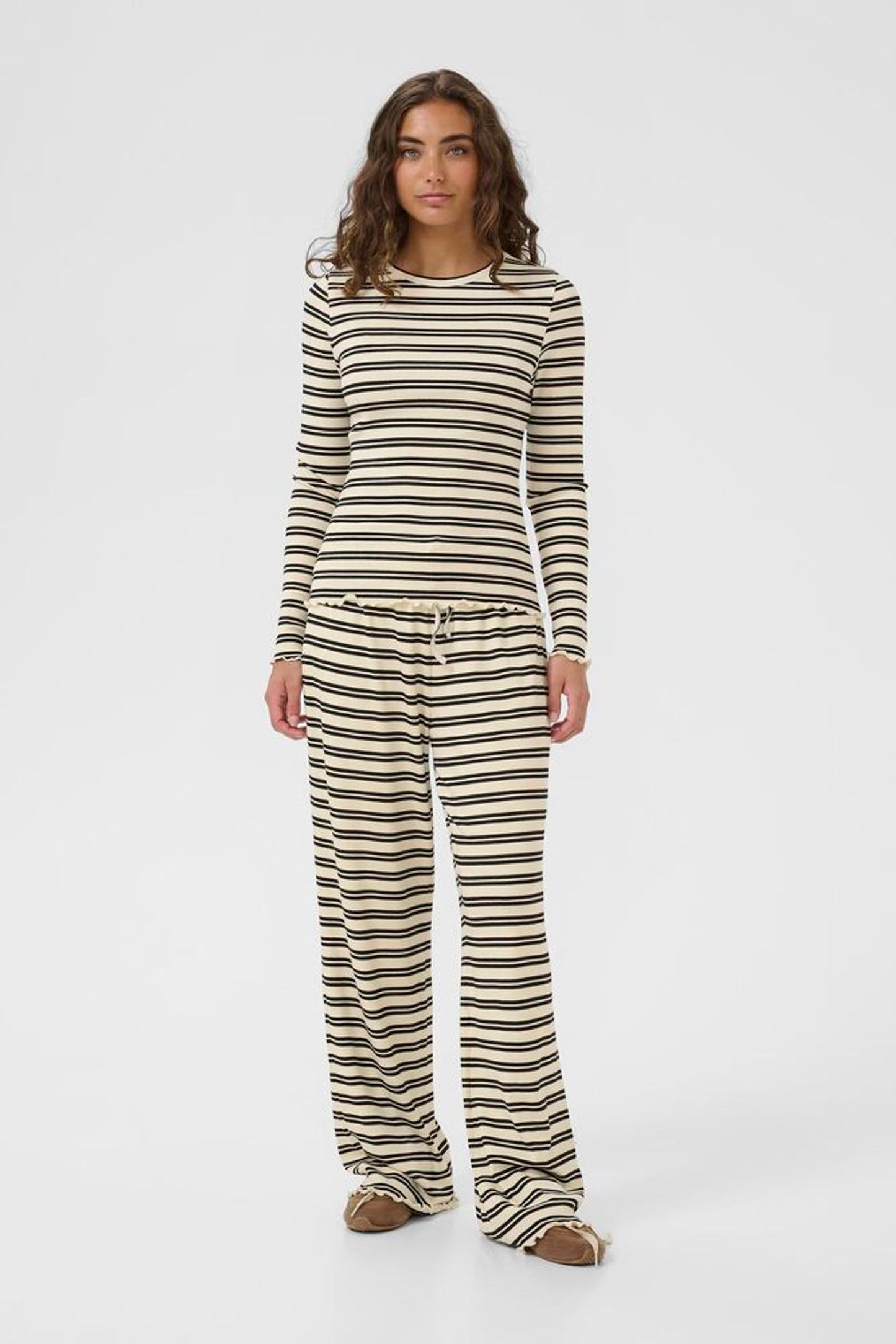 Woman wearing a striped long-sleeve top and pants on a white background