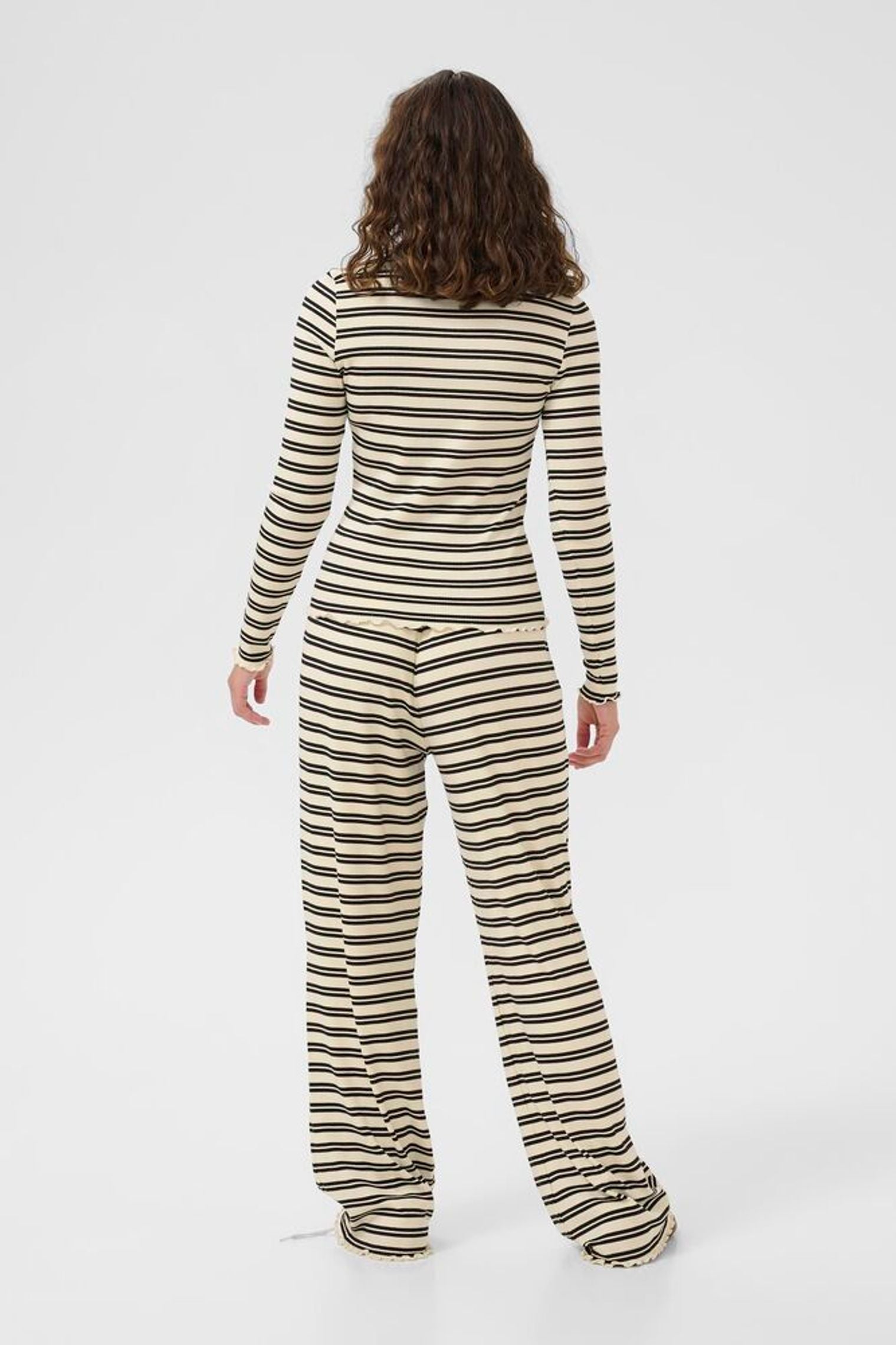 Person wearing a striped long-sleeve top and pants on a white background
