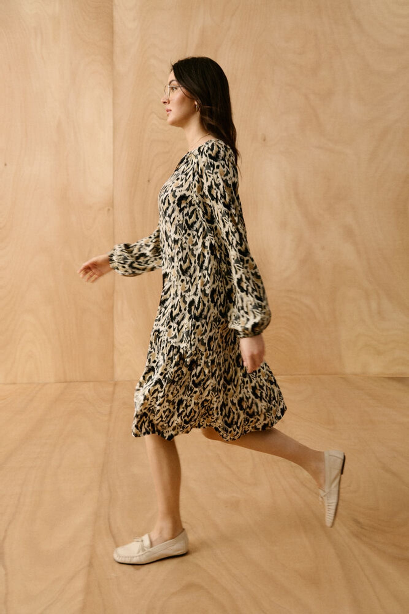 Woman wearing a leopard print dress against a beige wall
