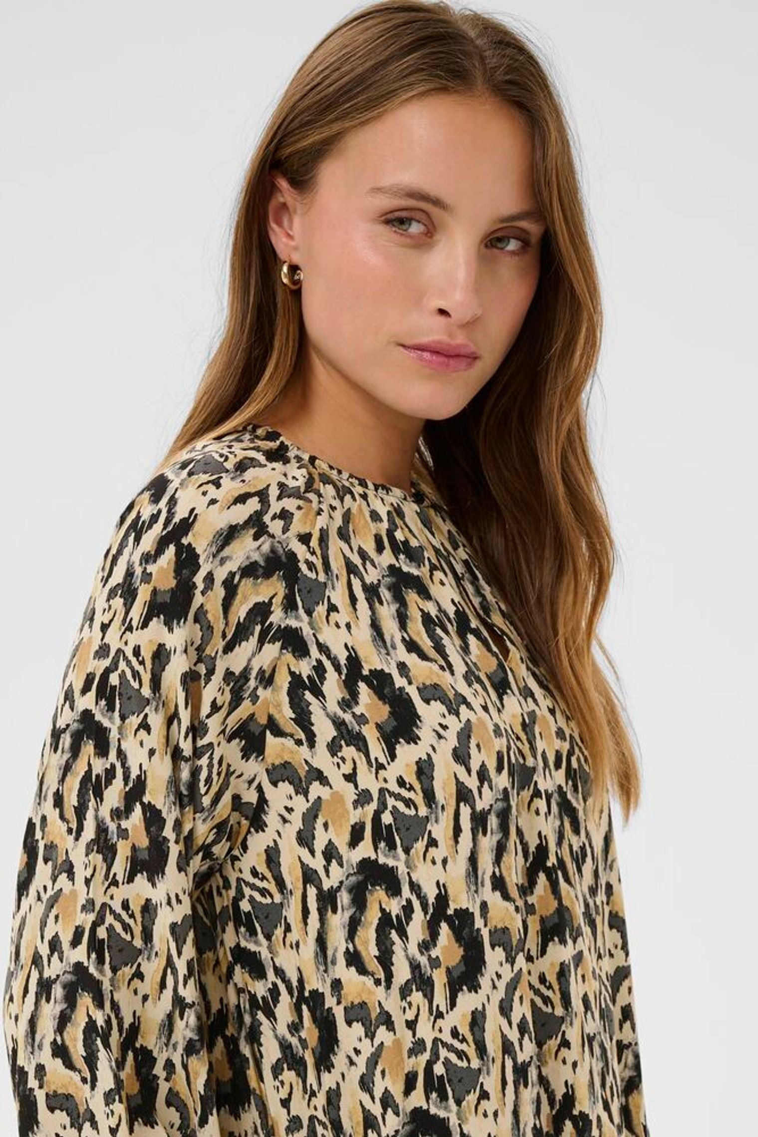 Woman wearing a leopard print dress against a plain background