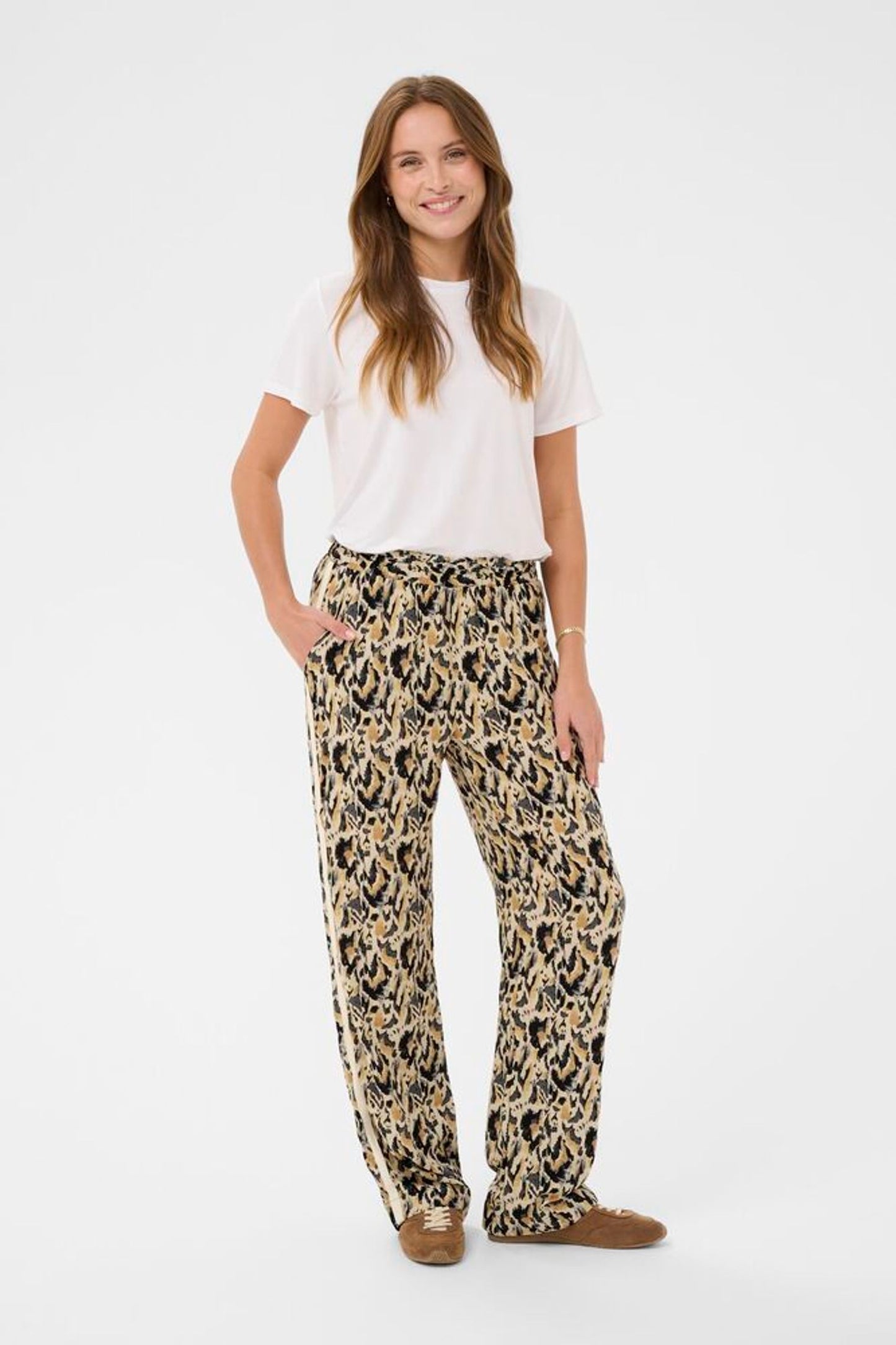 Woman wearing a white t-shirt and leopard print pants on a white background