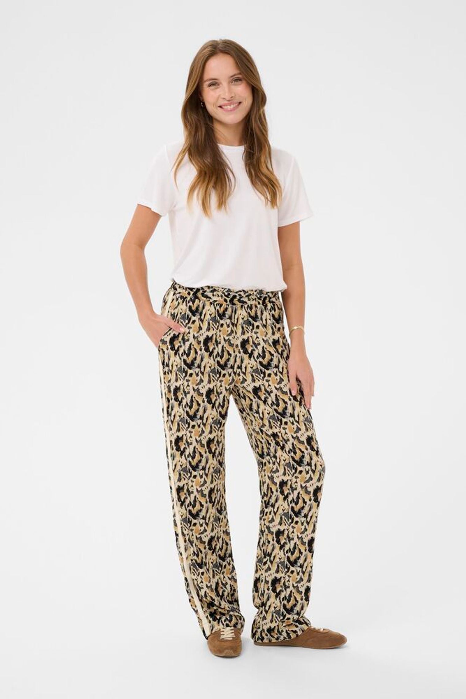 Woman wearing a white t-shirt and leopard print pants on a white background