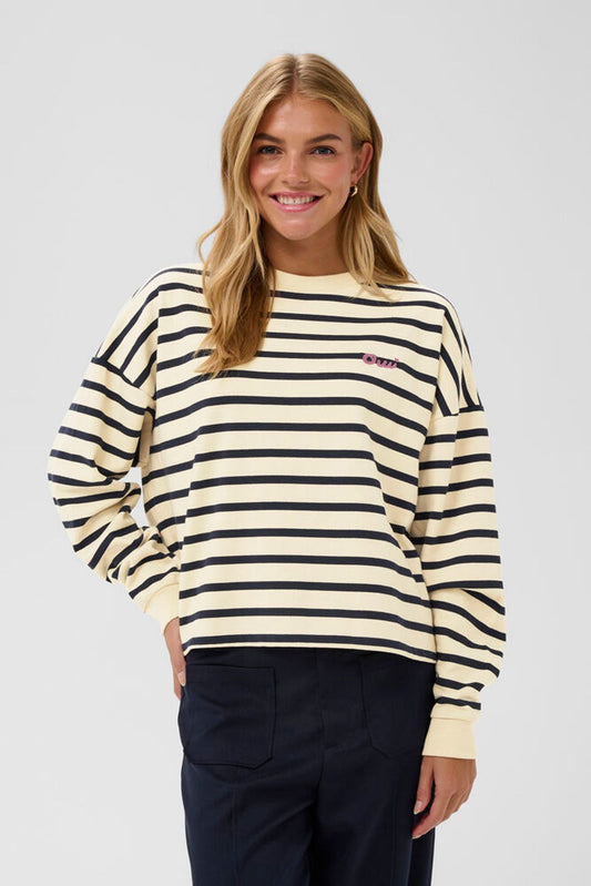 Woman wearing a striped sweater with a visible brand logo on a plain background