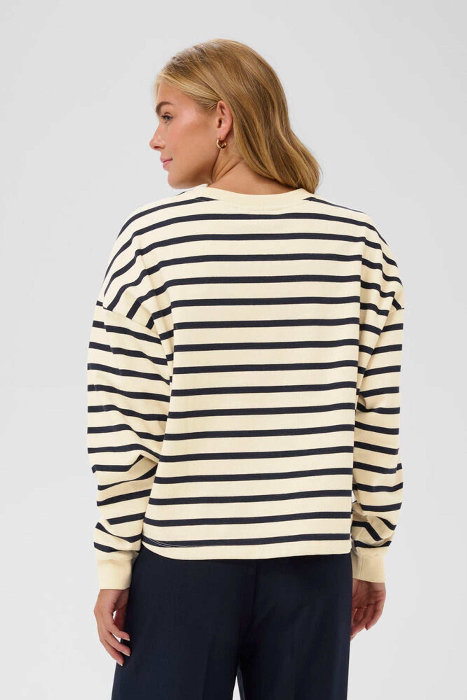 Woman wearing a striped sweater on a plain background