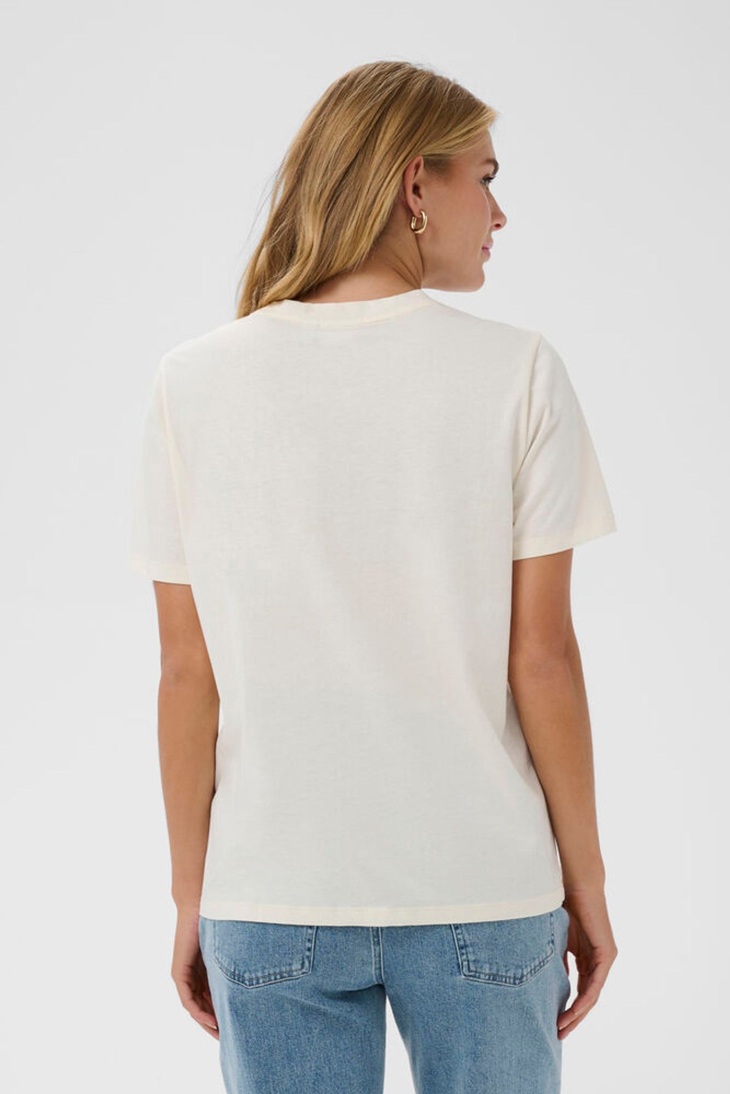 Woman wearing a plain white t-shirt and blue jeans on a light gray background