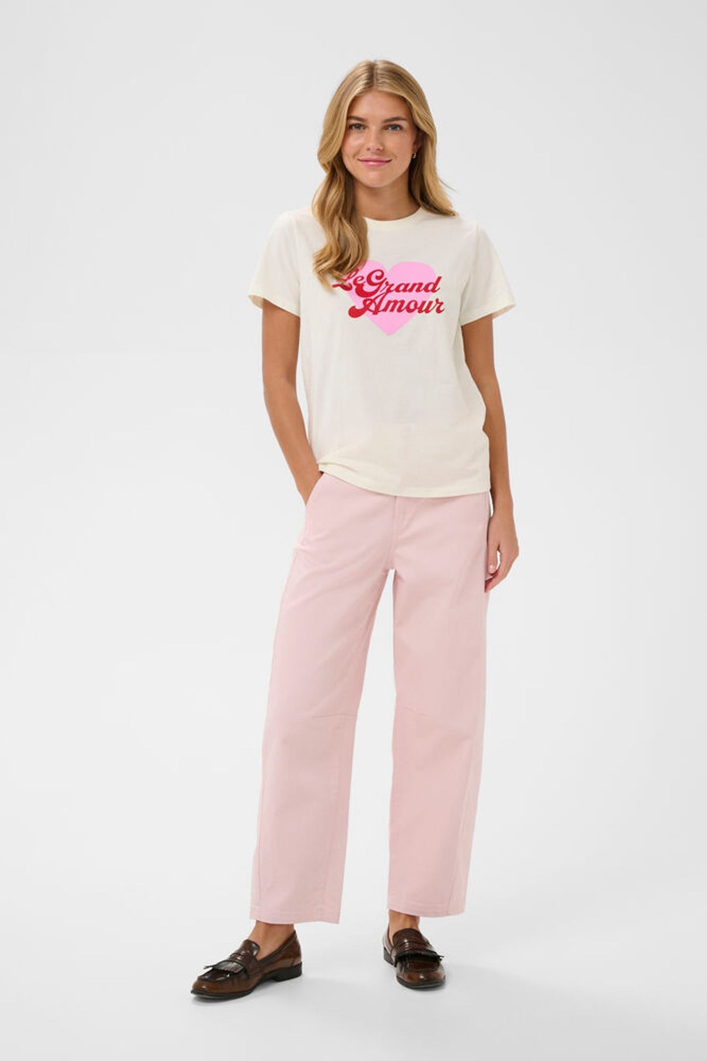 Woman wearing a white t-shirt with red text and pink pants on a white background