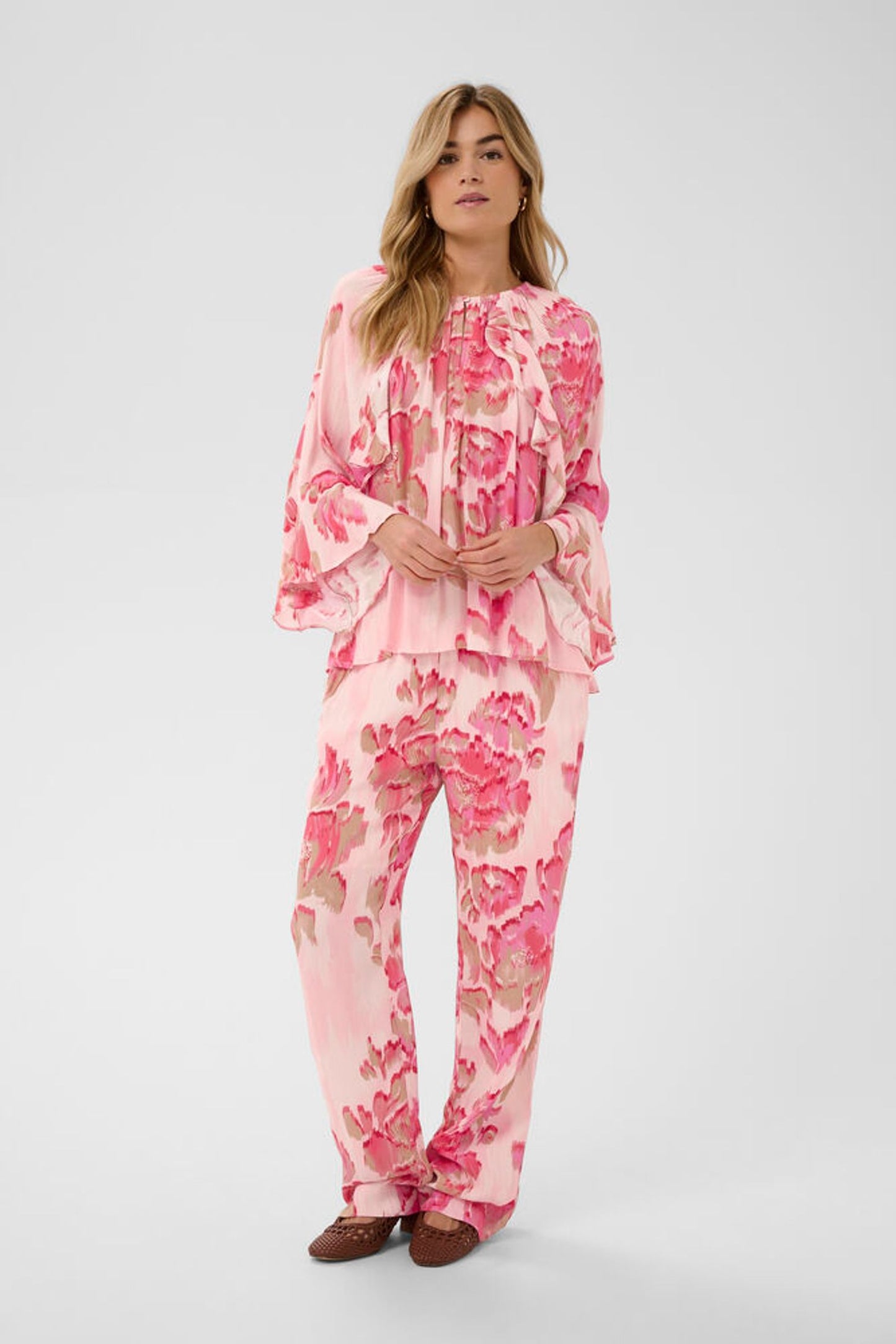 Woman wearing a pink floral outfit on a white background