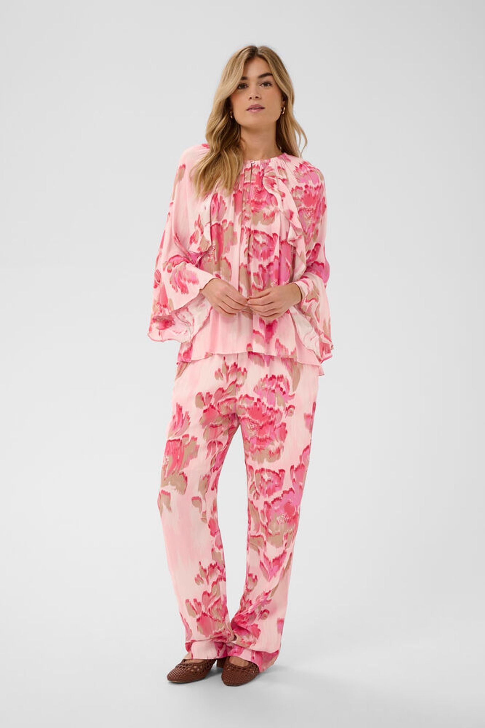 Woman wearing a pink floral outfit on a white background