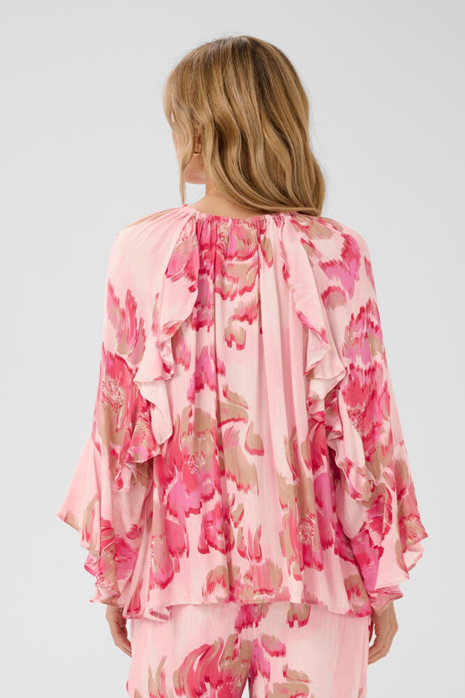 Woman wearing a pink floral outfit on a white background