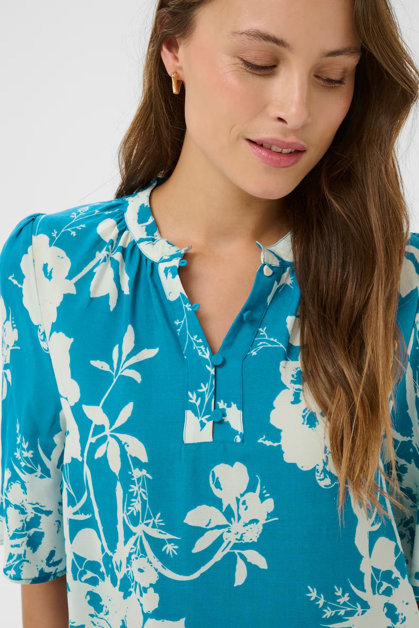 Woman wearing a blue floral blouse against a white background