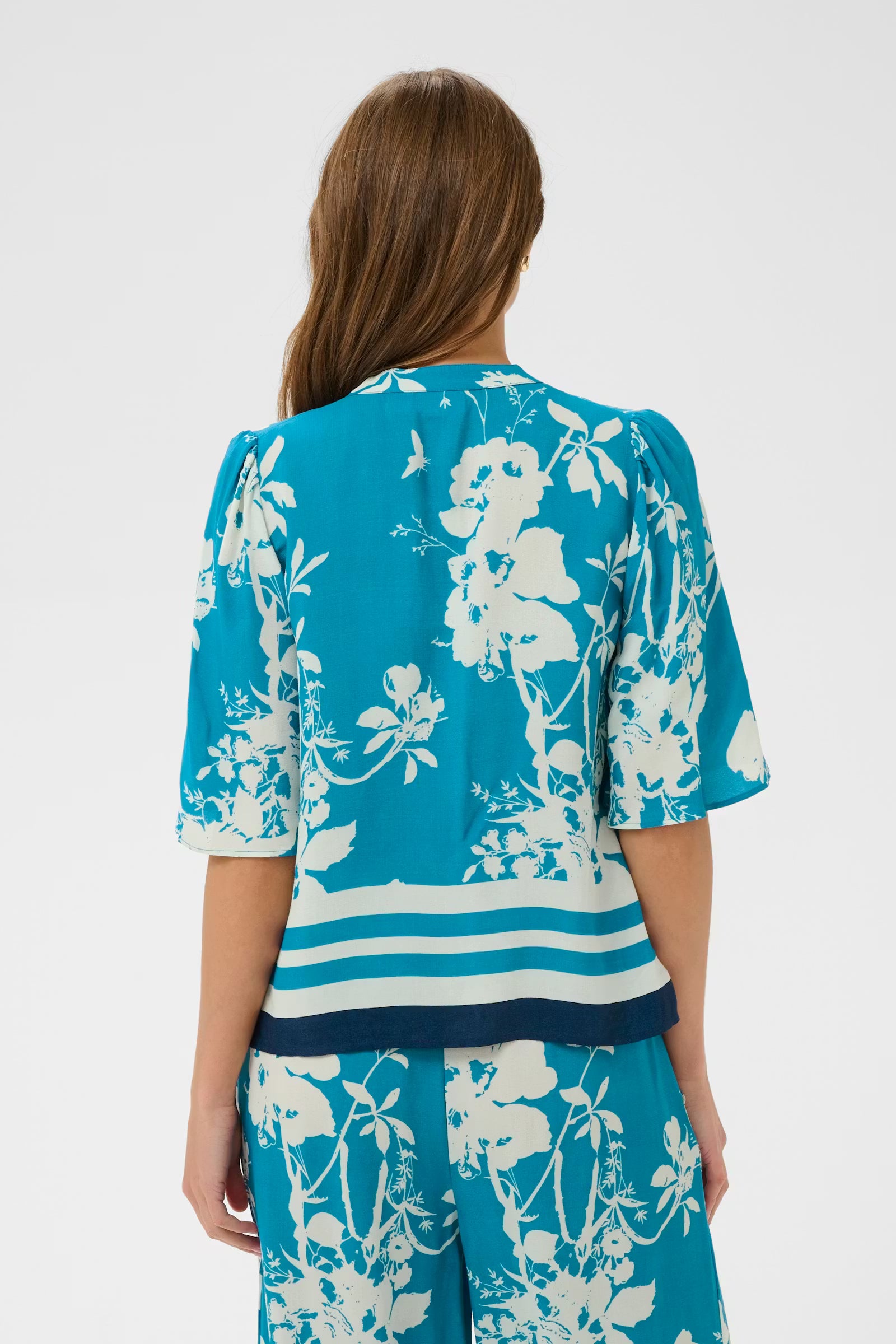 Woman wearing a blue and white floral outfit on a white background