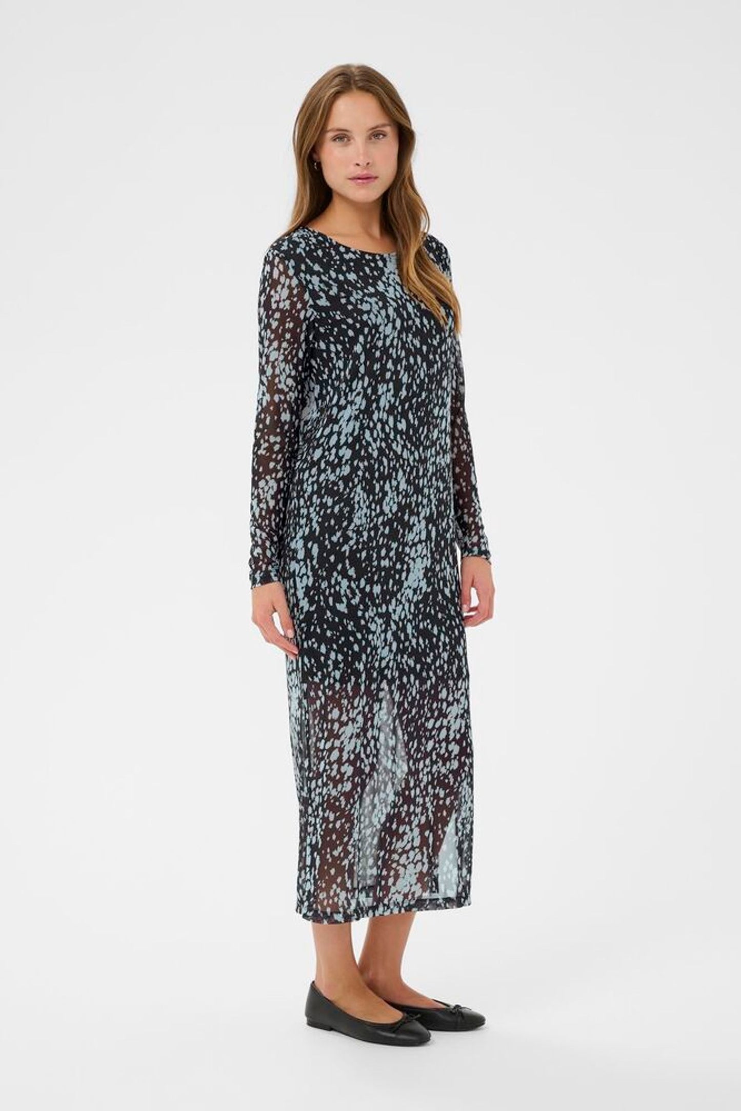 Woman wearing a long, patterned dress on a white background