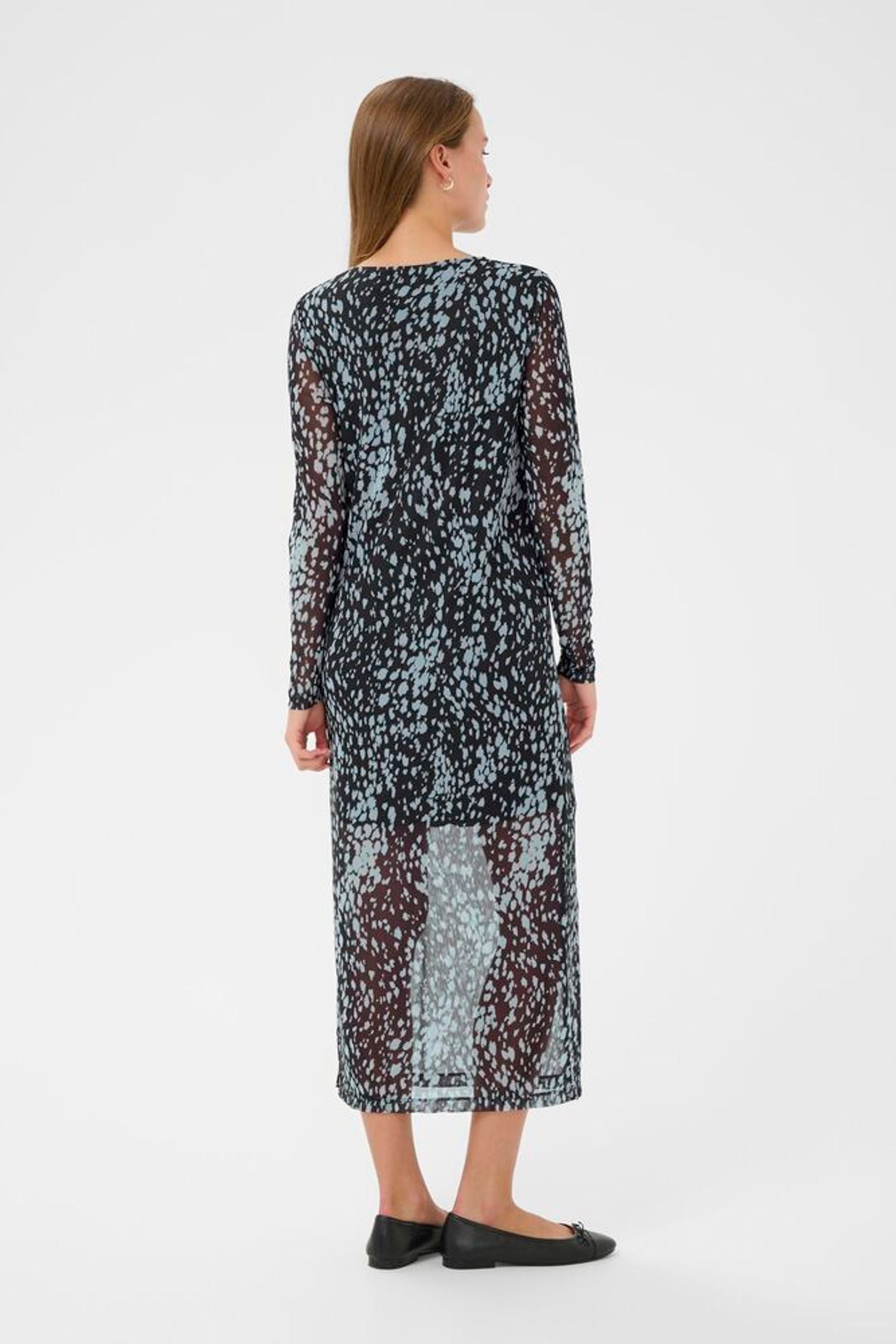 Woman wearing a long, sheer dress with a floral pattern on a white background