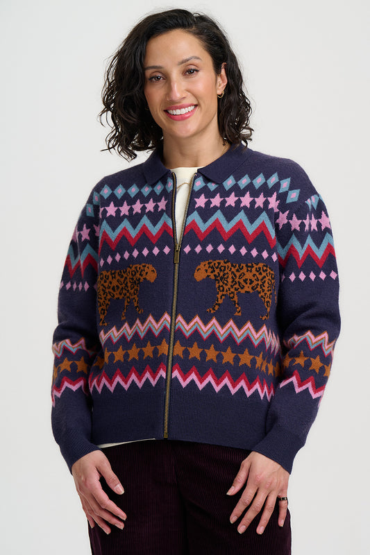 Woman wearing a navy blue zip-up sweater with colorful patterns and animal designs on a white background