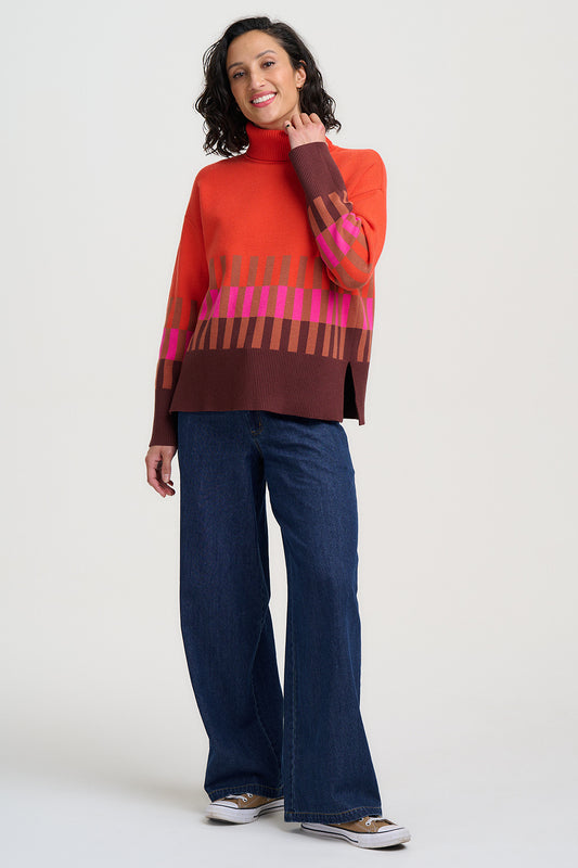 Woman wearing a colorful sweater and blue jeans on a white background