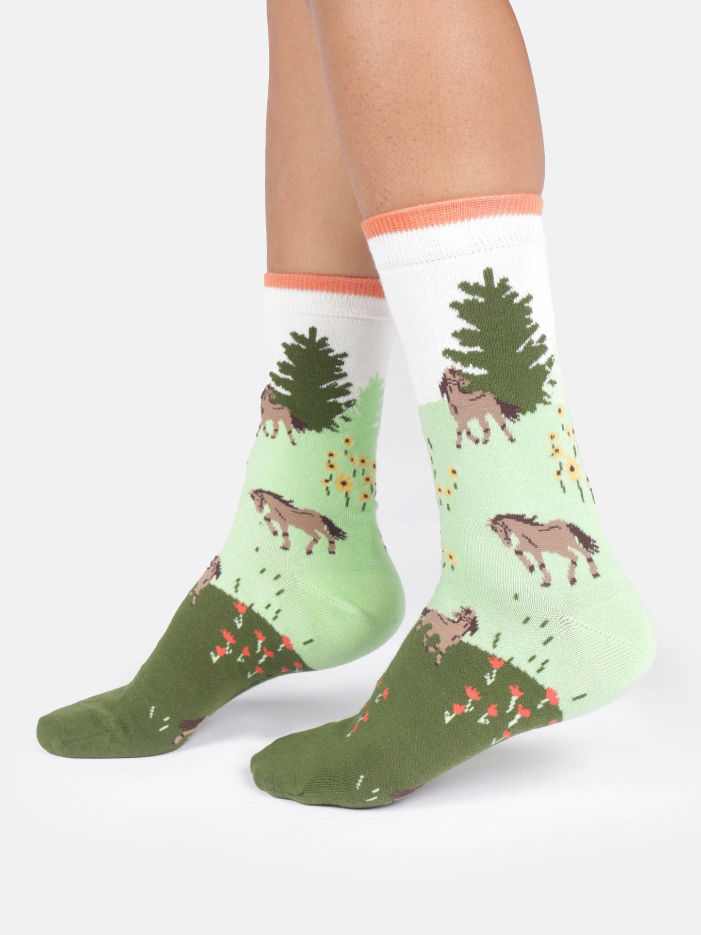 Green and white socks with horse and tree design worn by a person on a white background