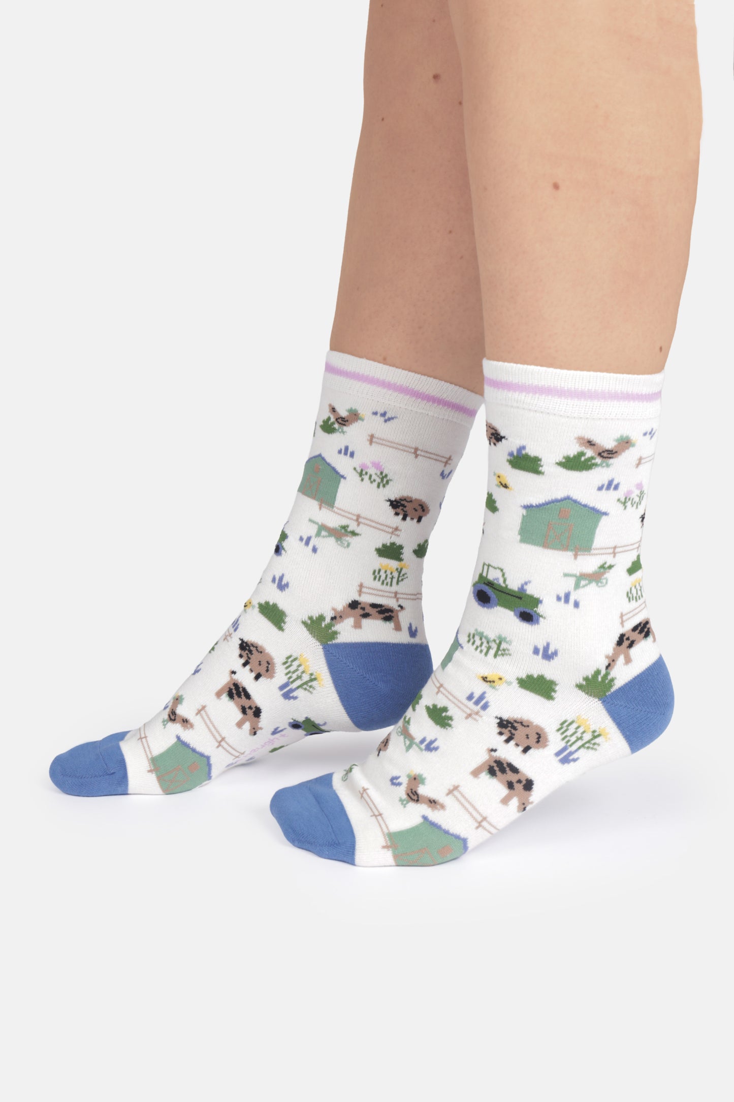 White socks with farm animal pattern worn by a person on a white background