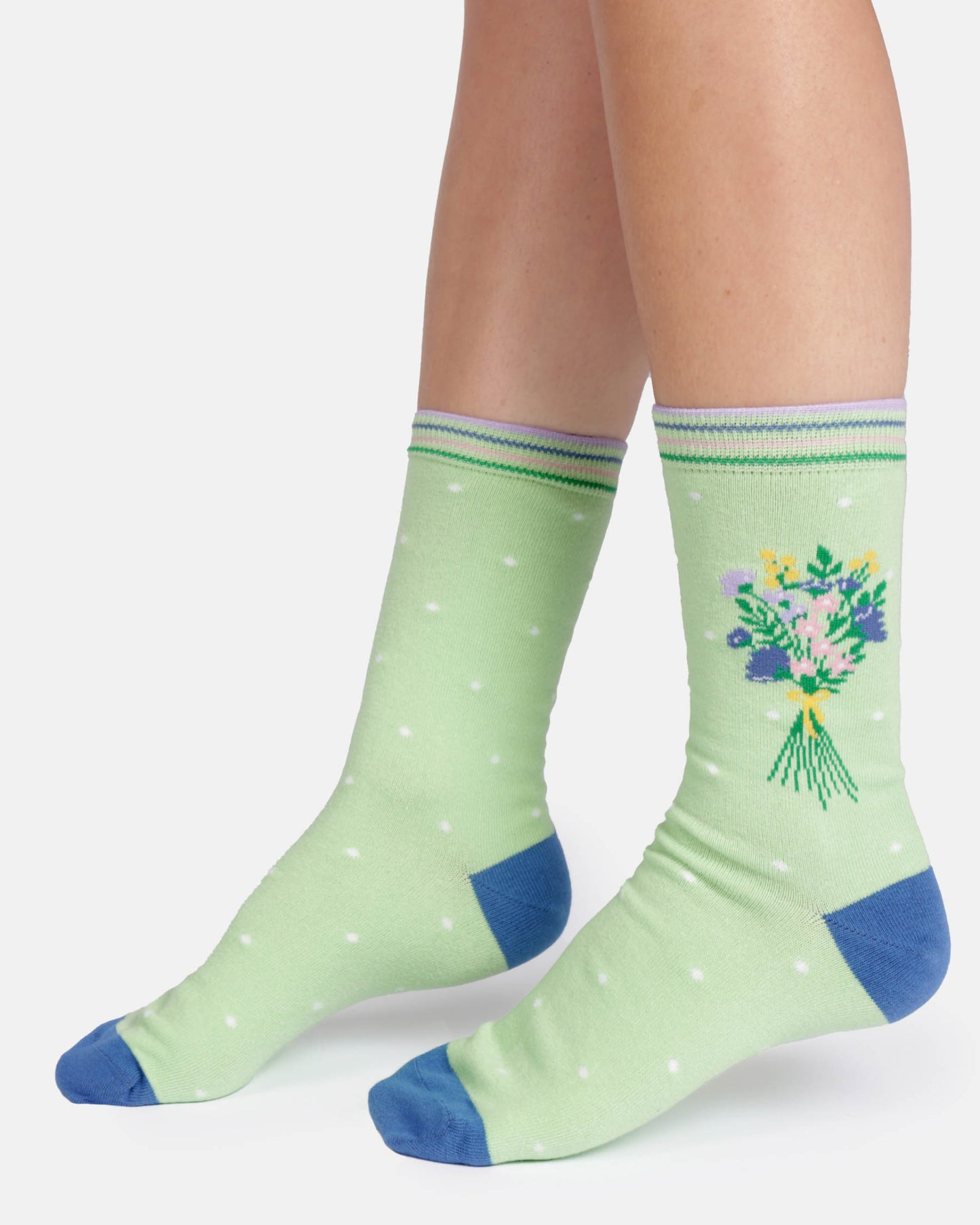 Green socks with floral design and blue accents worn by a person on a white background