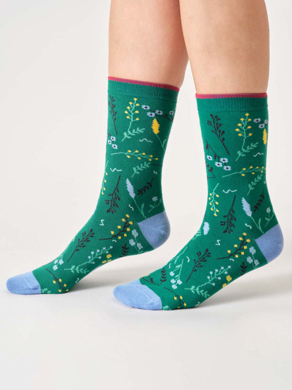 Green socks with floral pattern worn by a person on a white background