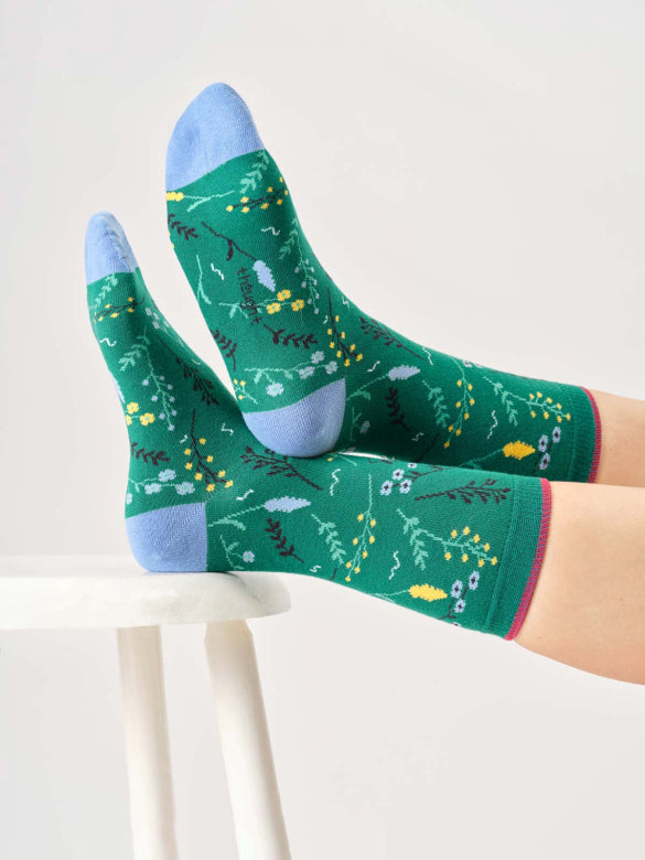 Green socks with floral pattern worn by a person on a white background