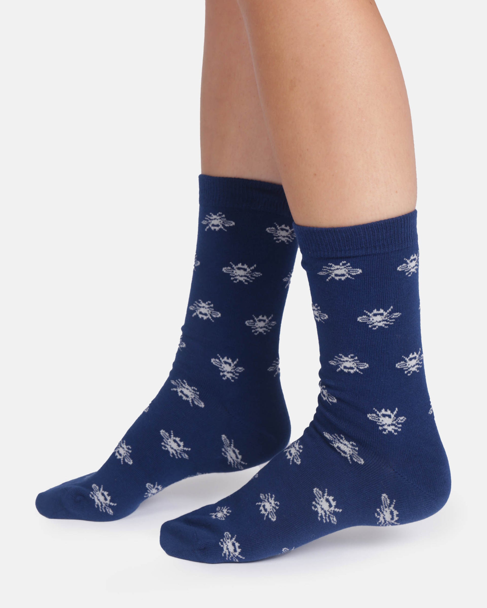 Navy blue socks with white bee pattern worn by a person on a white background