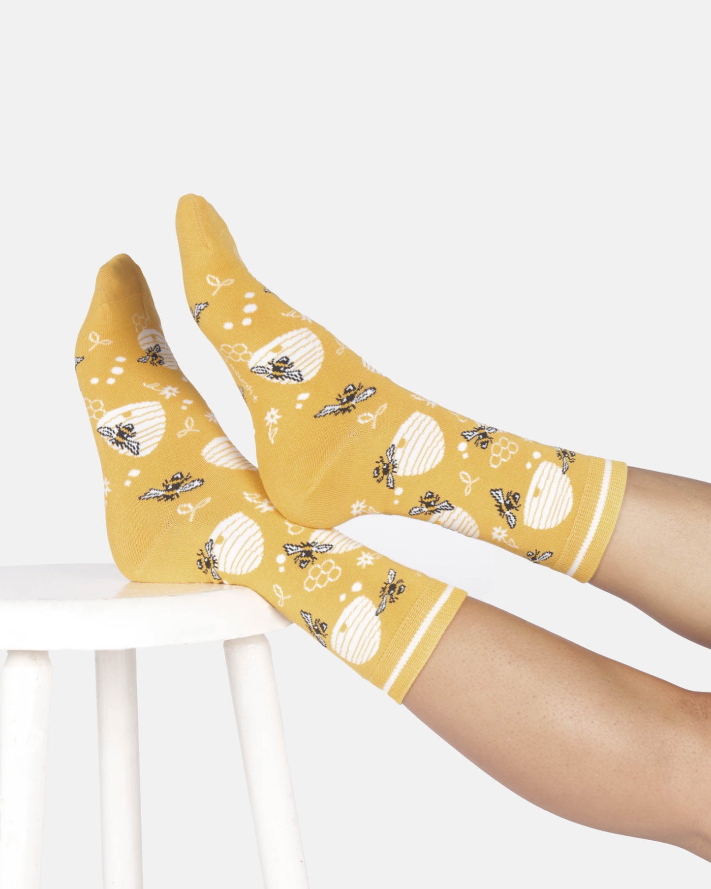 Yellow socks with bee pattern worn by a person on a white background
