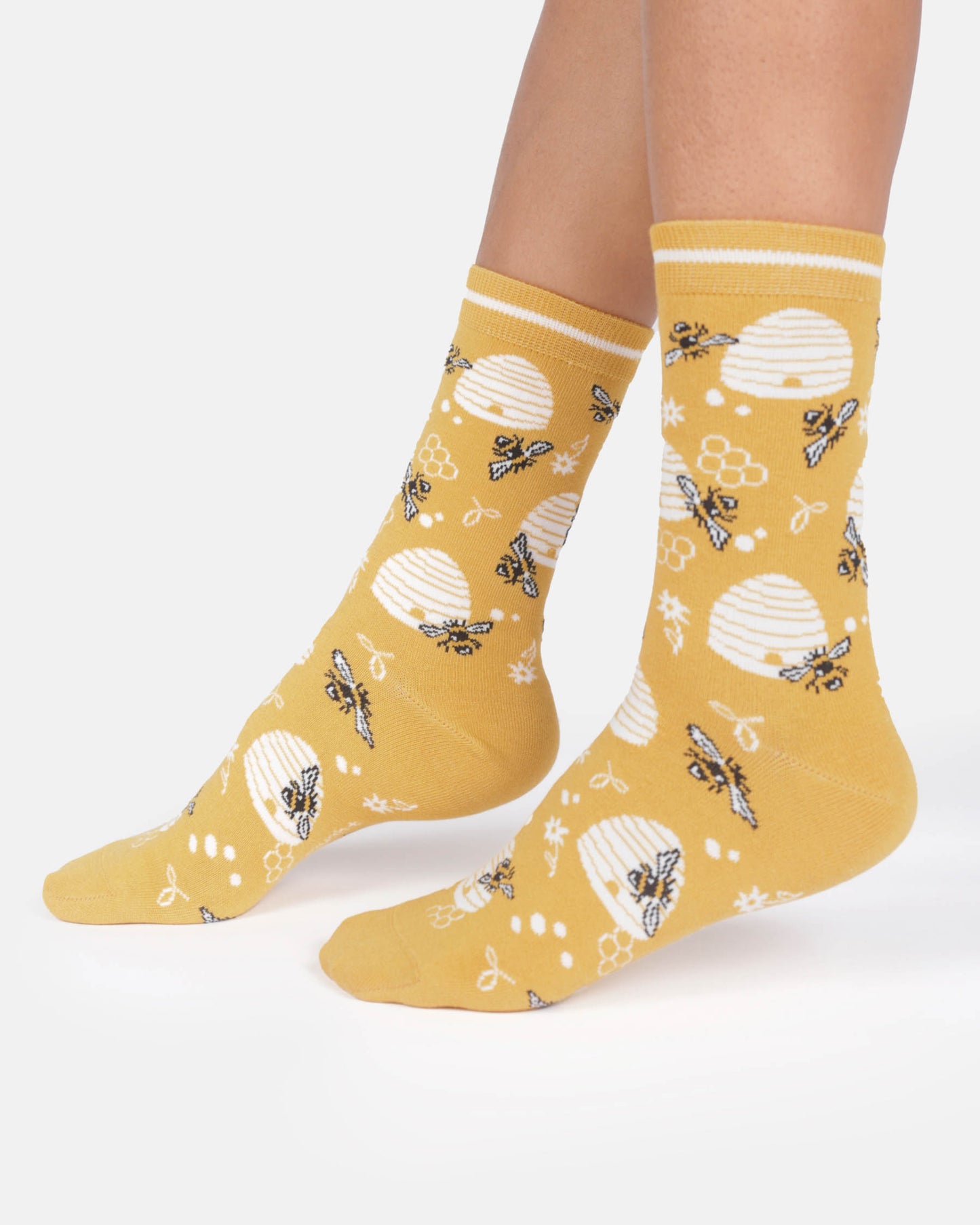 Yellow socks with bee and honeycomb pattern worn by a person on a white background