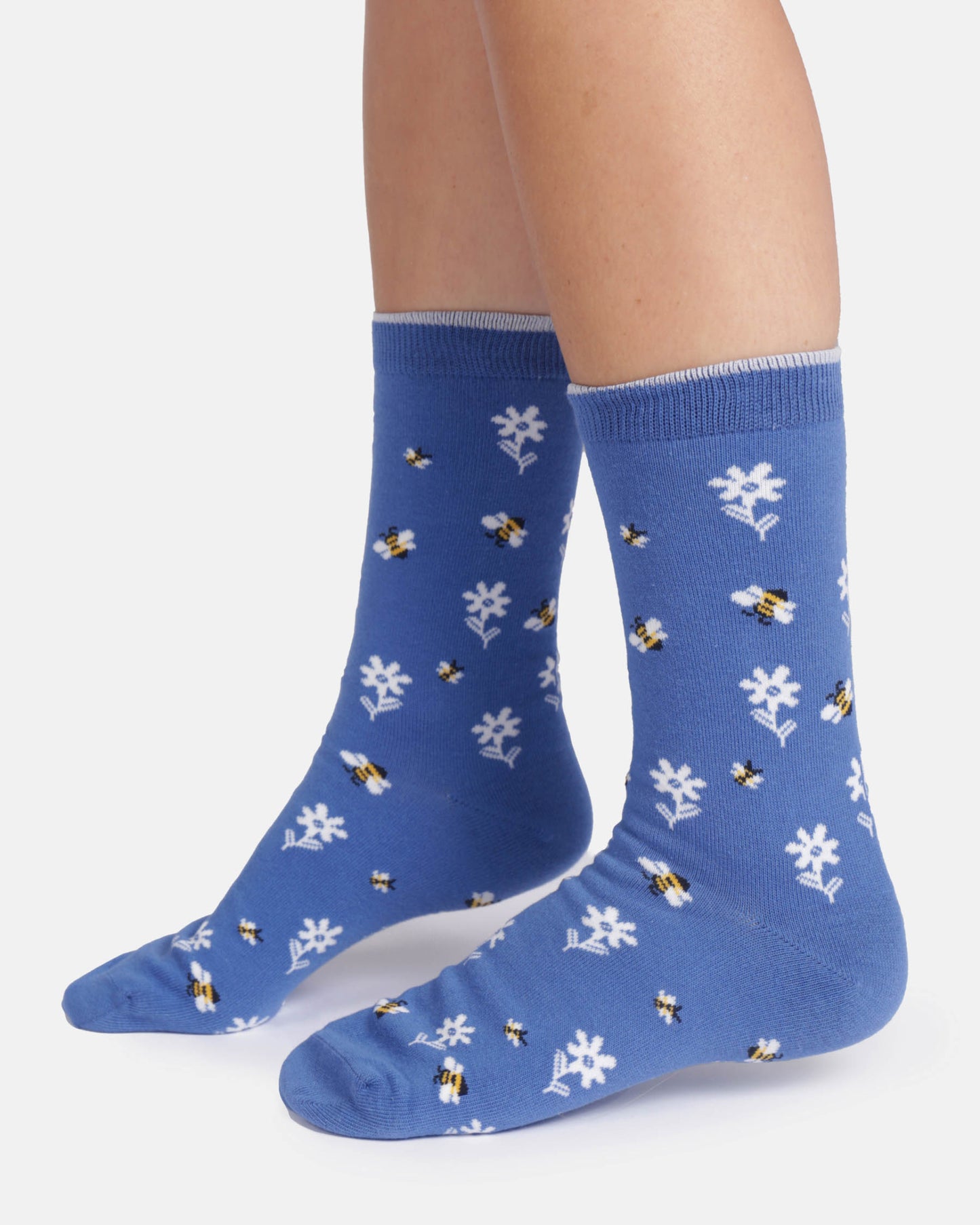 Blue socks with white flower and bee pattern worn by a person on a white background