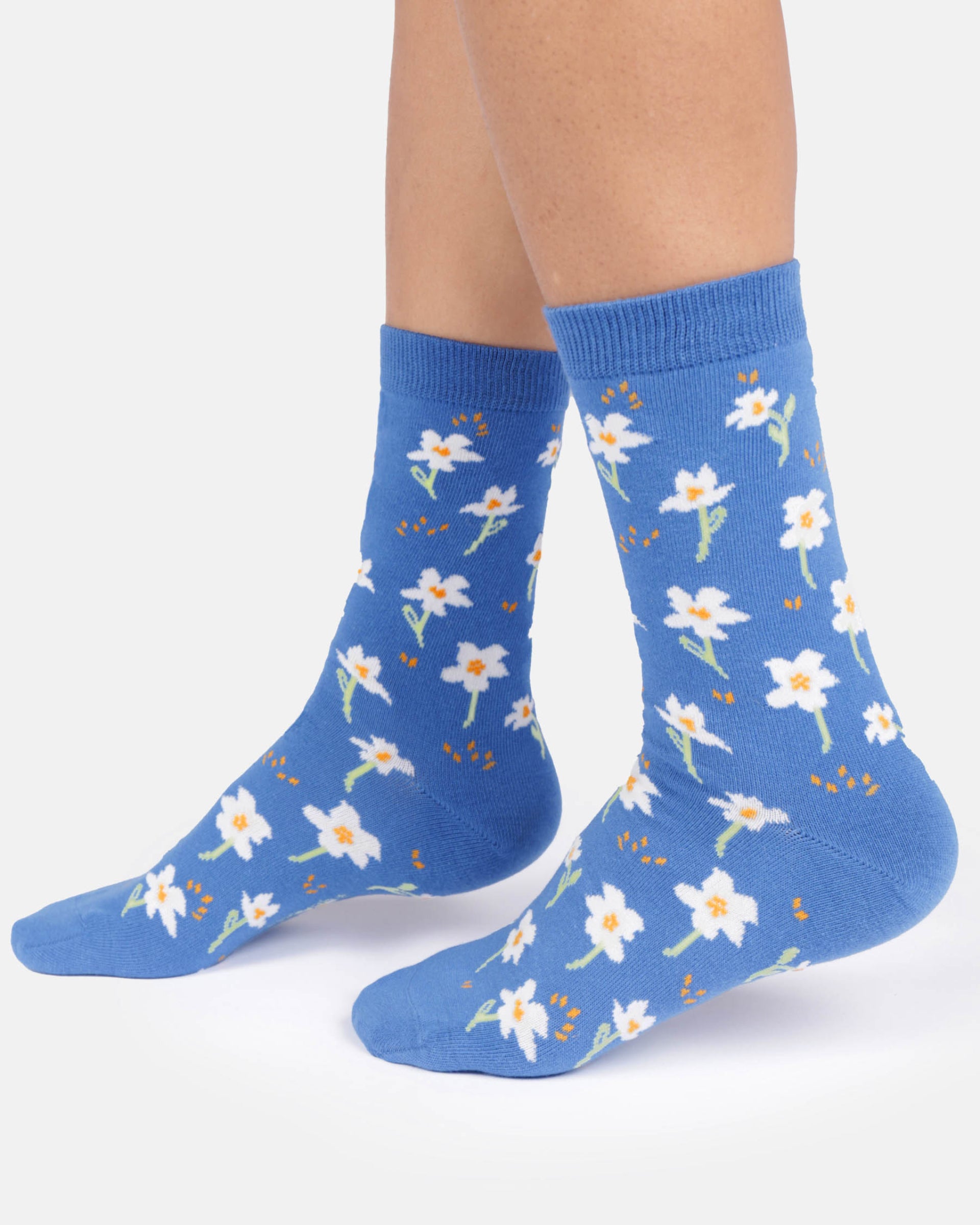 Blue socks with white floral patterns worn by a person on a white background