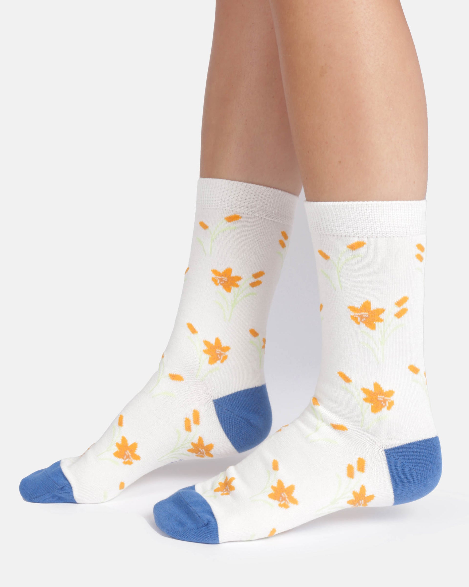 White socks with orange floral patterns and blue toes and cuffs worn by a person on a white background