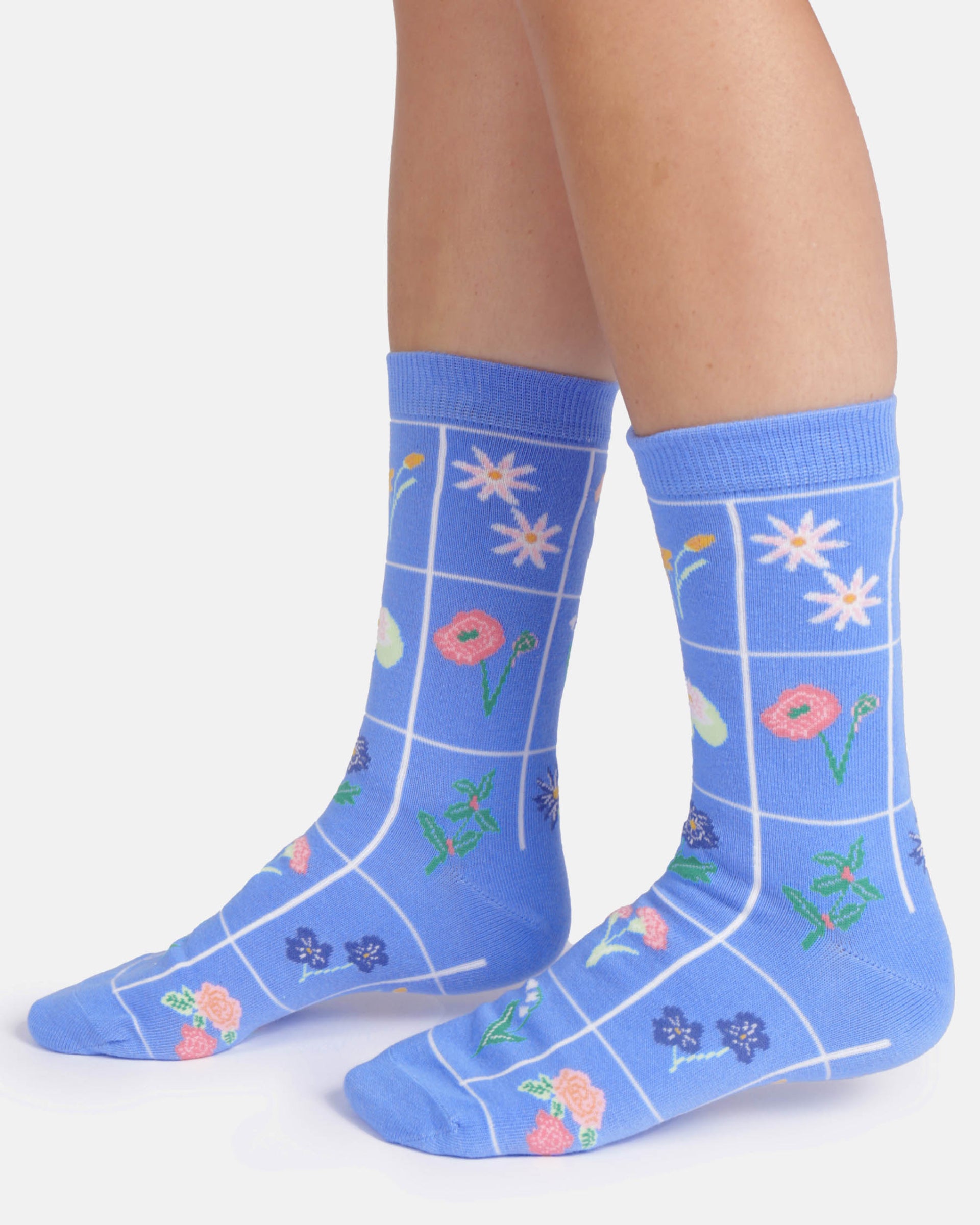 Blue socks with floral patterns worn by a person on a white background