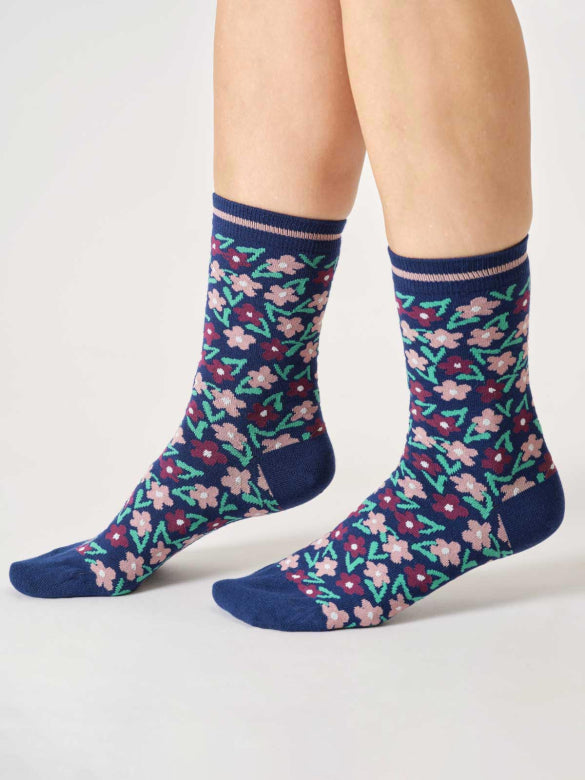 Navy socks with floral pattern worn by a person on a white background