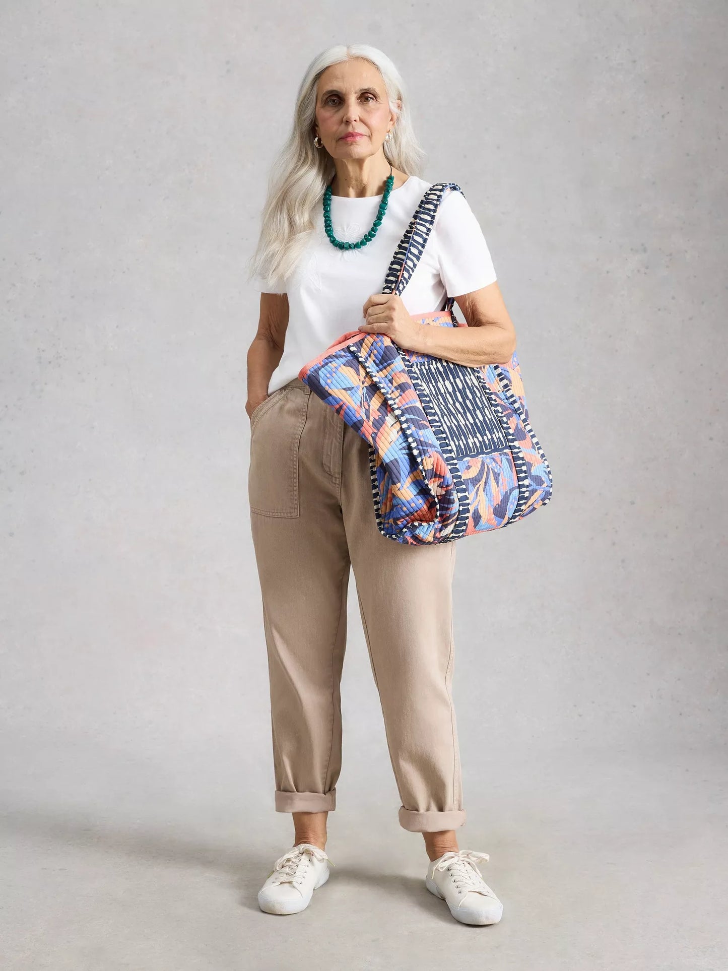 Woman holding a colorful bag against a plain background