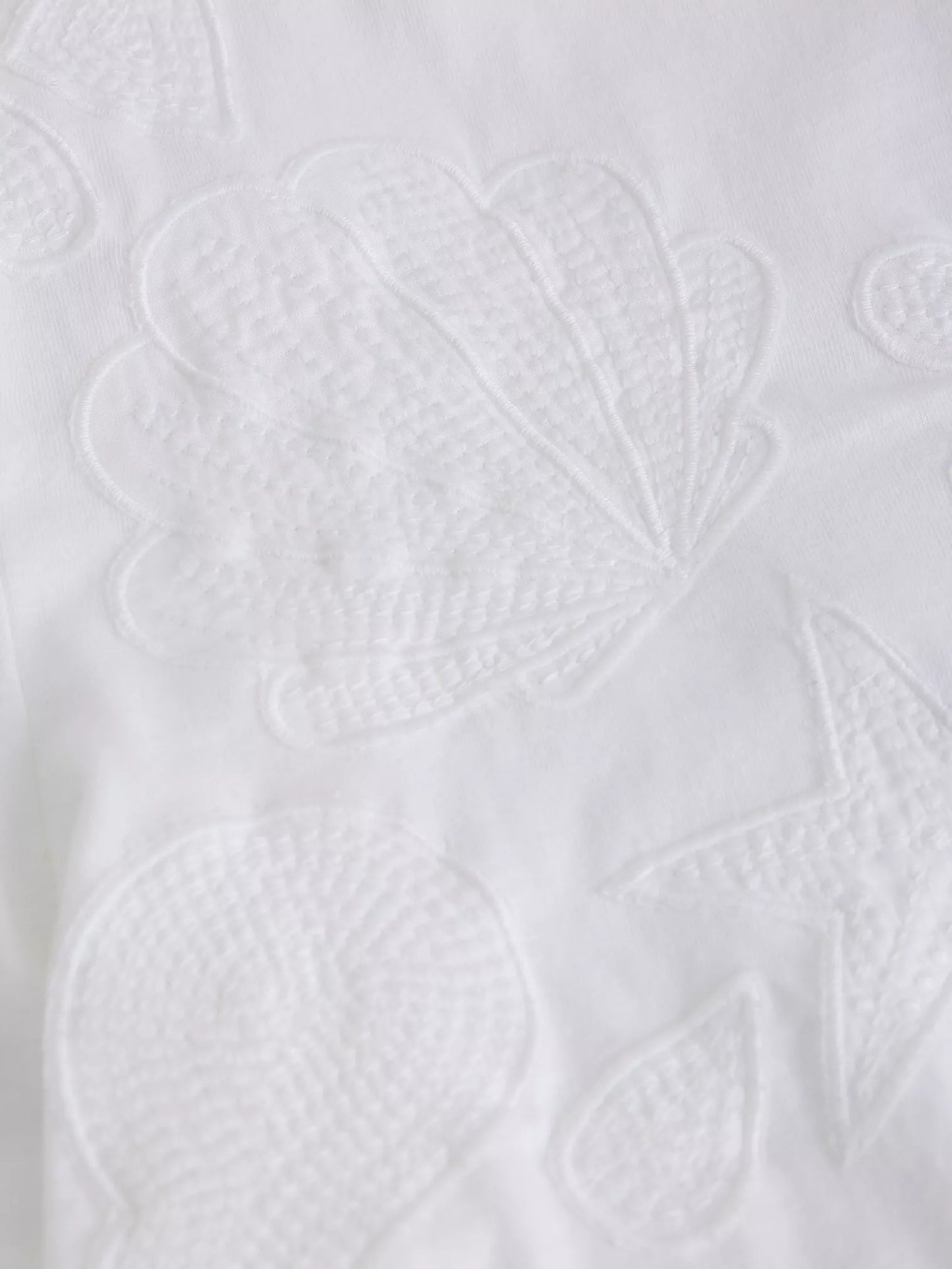 Close-up of a white textured fabric with leaf patterns