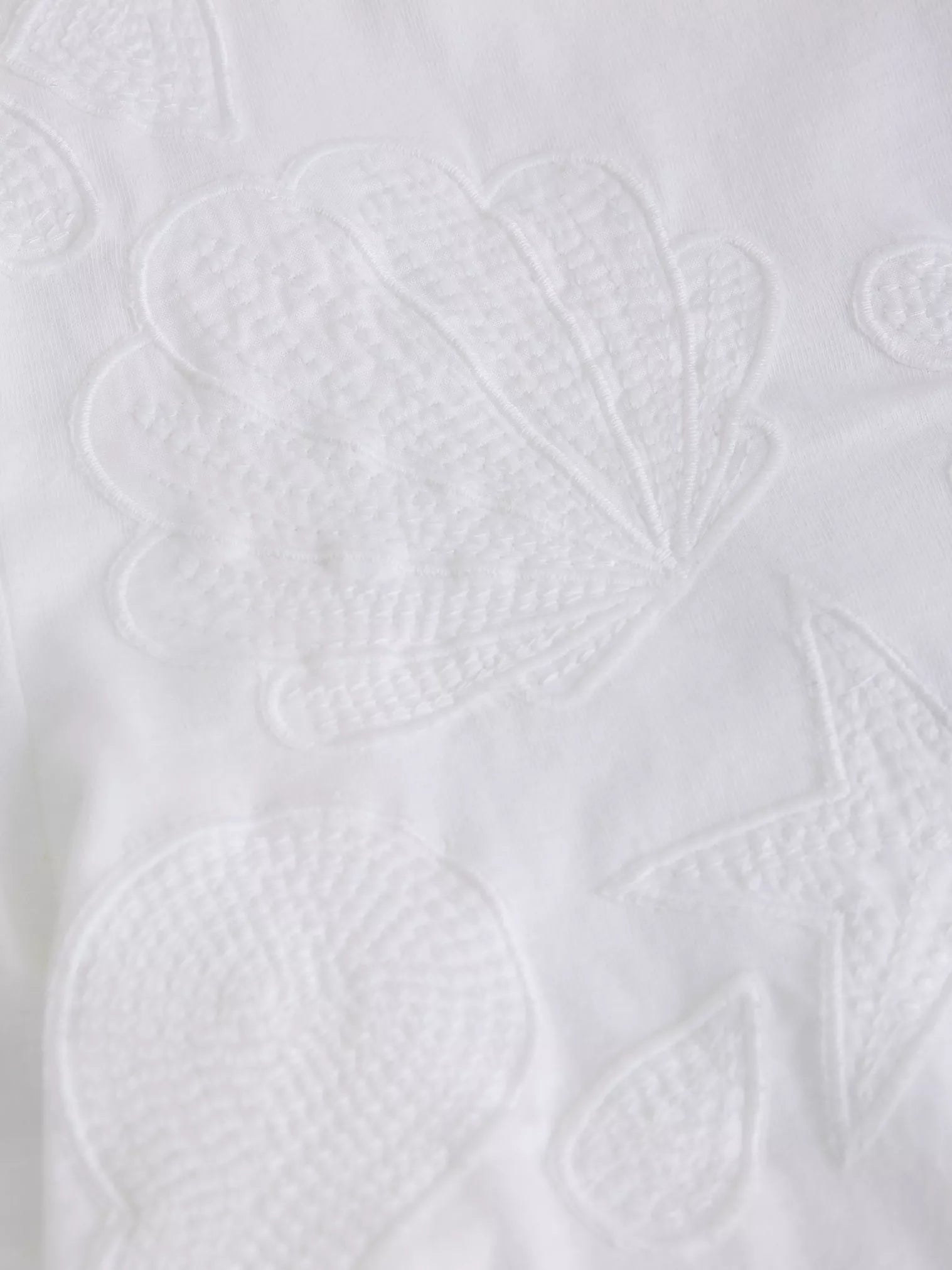Close-up of a white textured fabric with leaf patterns