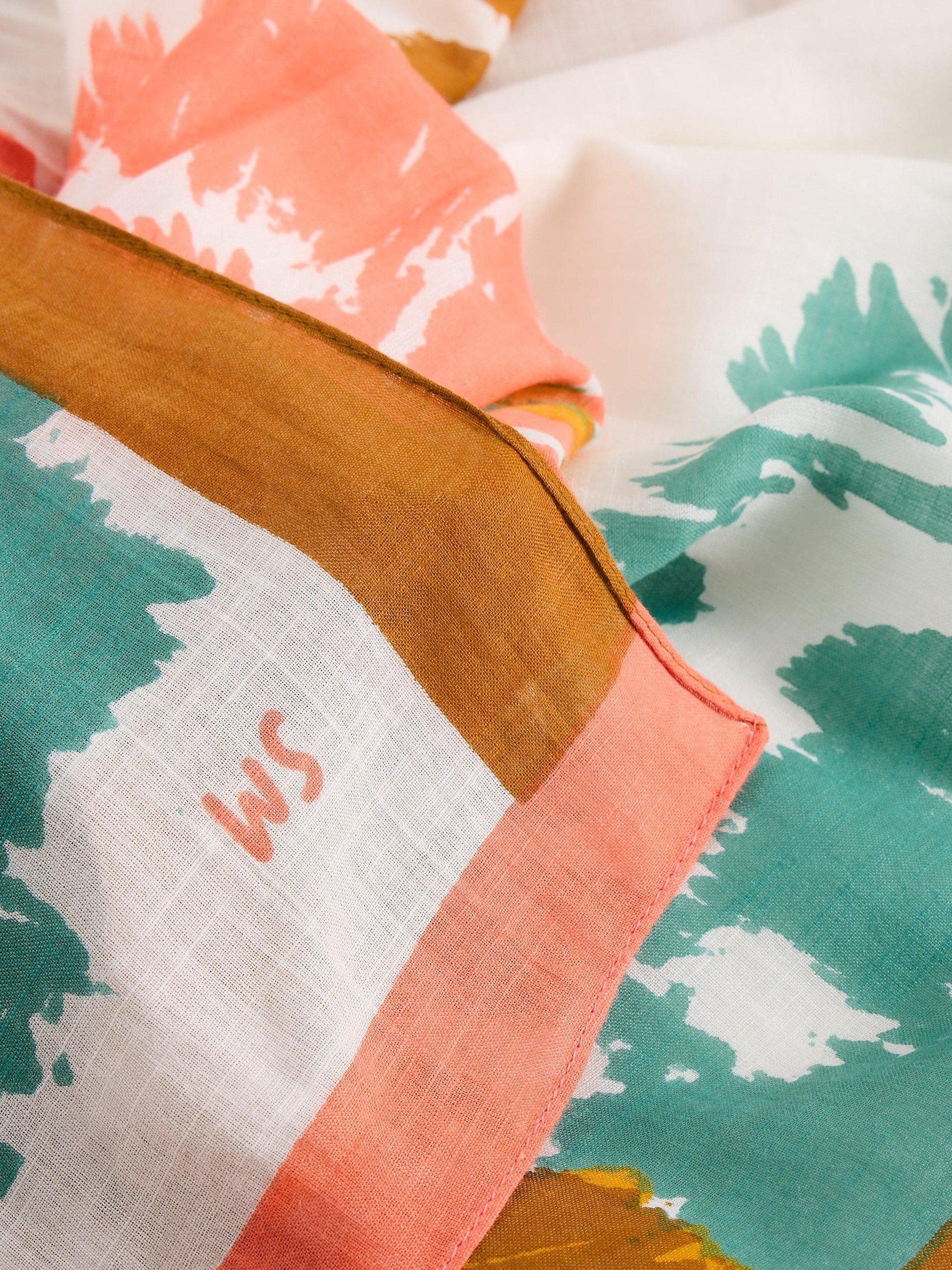 Close-up of a fabric with colorful floral patterns and a brand logo.